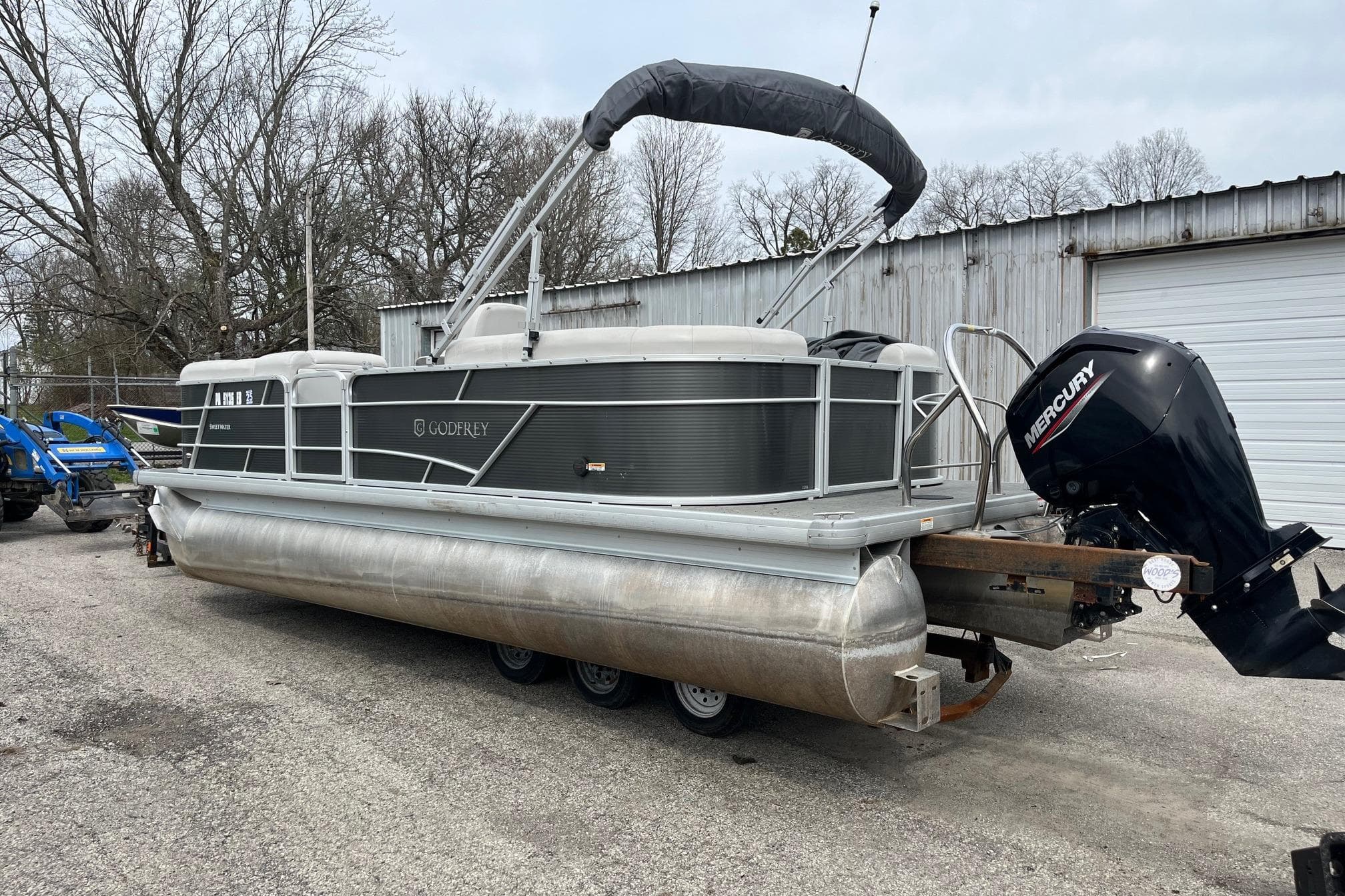 2022 Godfrey Sweetwater 2286 SBX pontoon boat with Mercury outboard motor in a yard.
