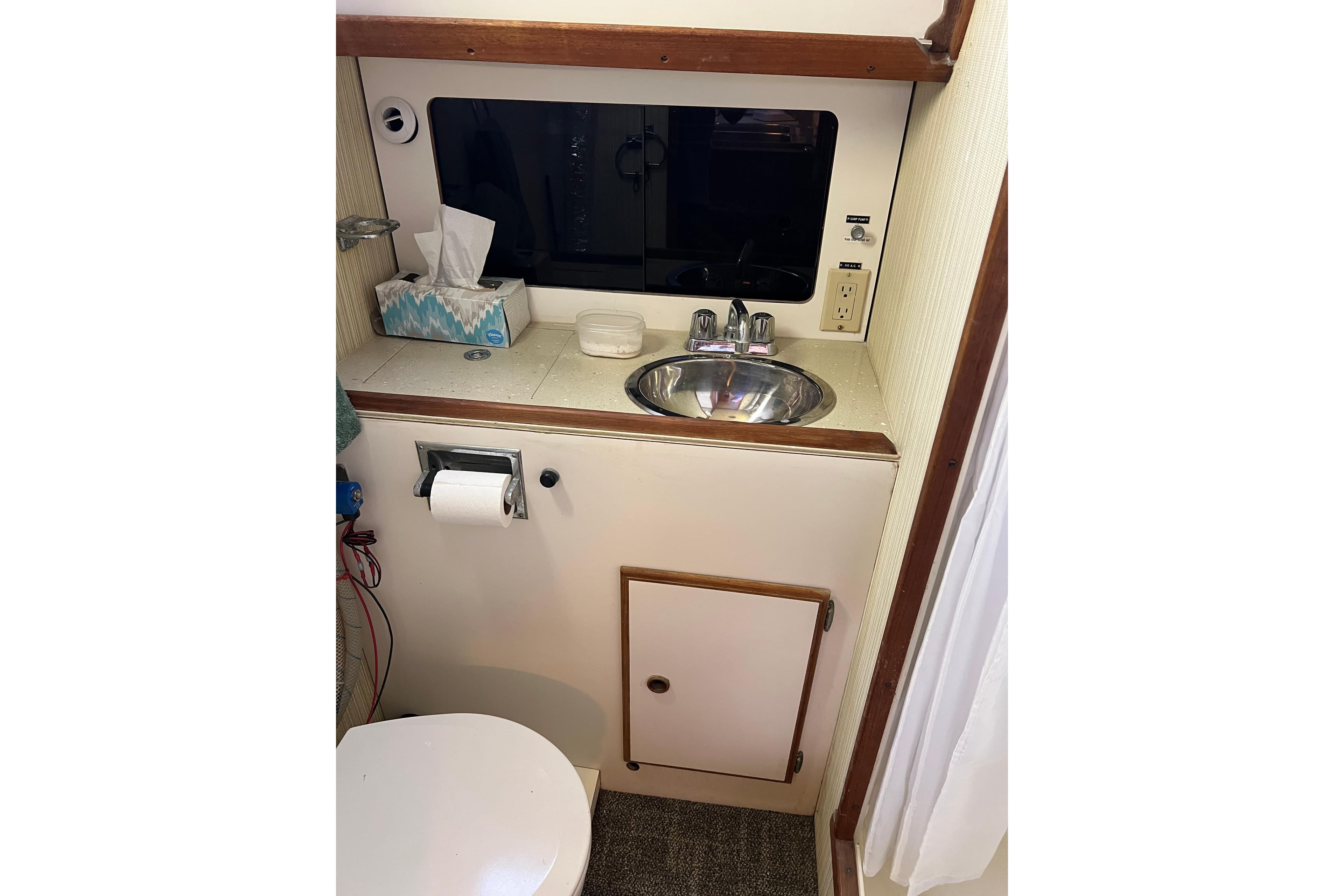 1979 Pearson 424 boat bathroom with sink, mirror, and toilet paper holder.