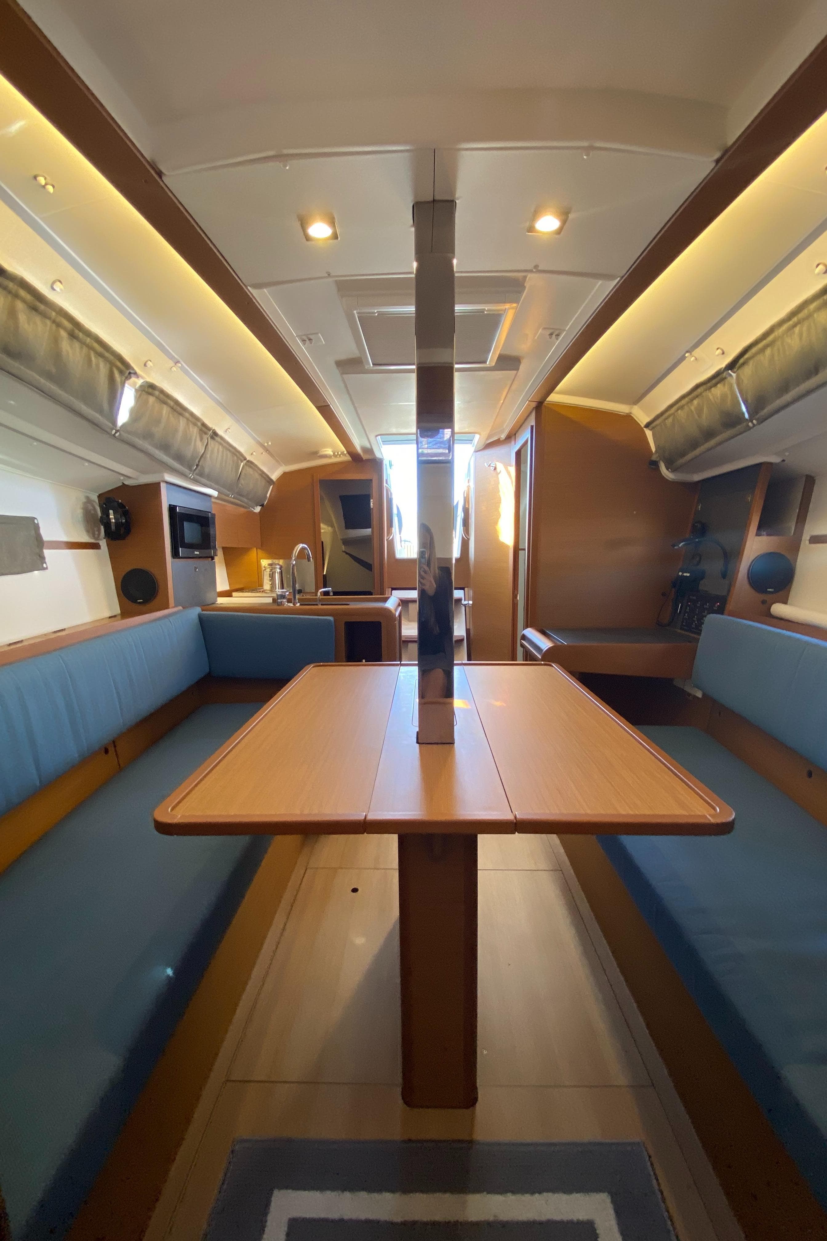 2023 Jeanneau Sun Odyssey 349 interior with blue seating and wooden table.