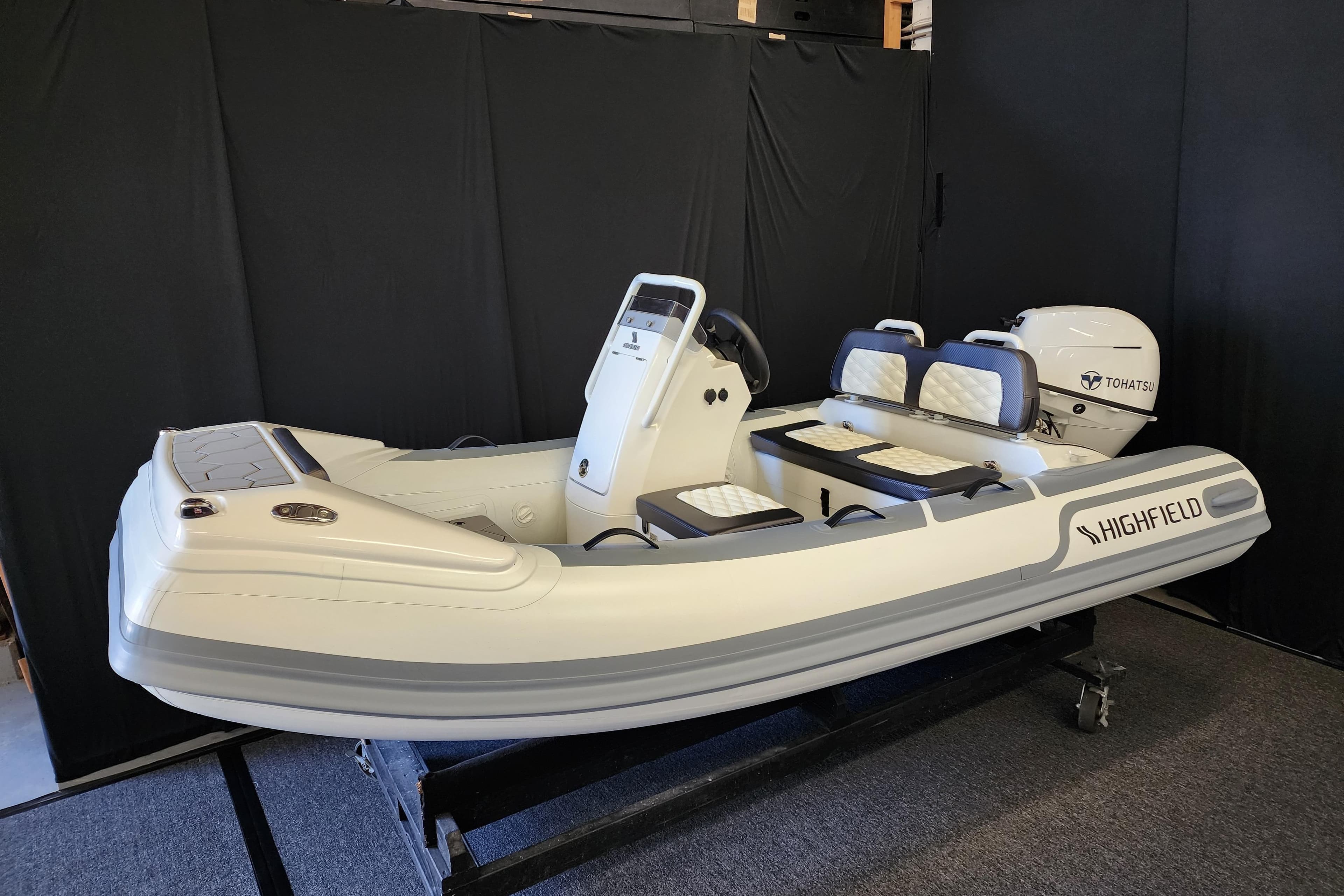 2026 Highfield Sport 330 inflatable boat with Tohatsu engine, displayed indoors.