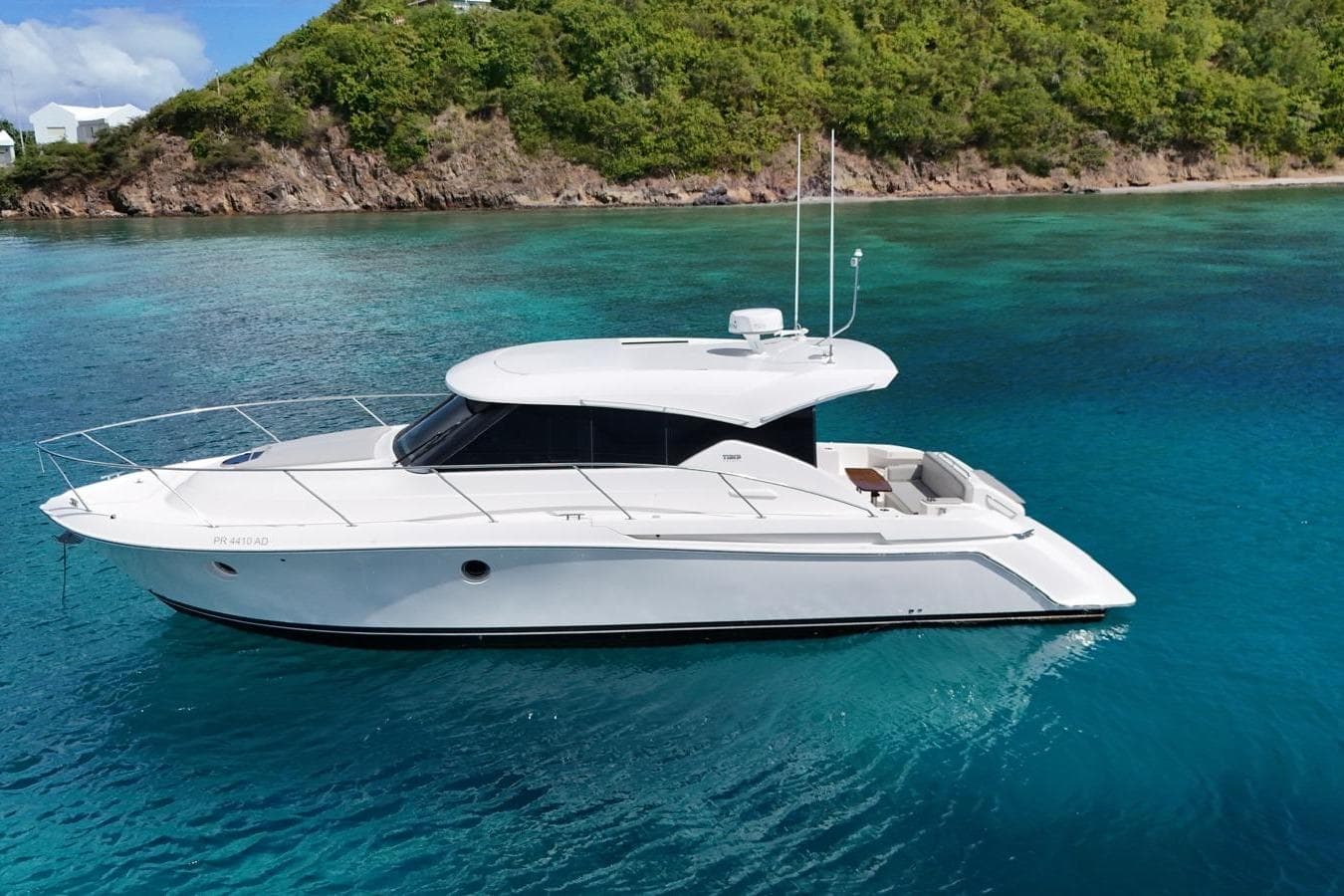 2022 Tiara Yachts C39 Coupe on clear blue water near lush green island.