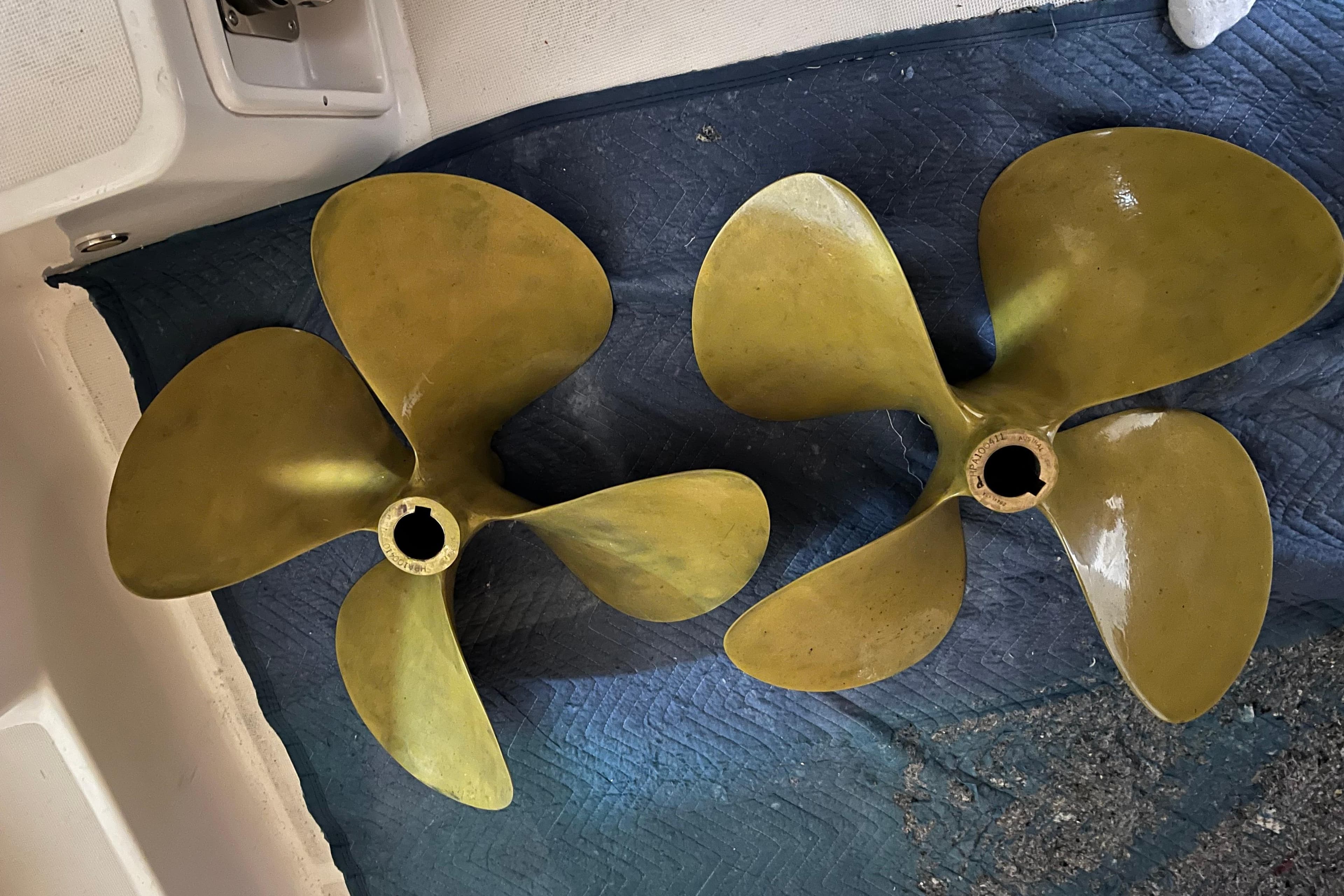 Two brass propellers for a 2009 Tiara Yachts 4200 Open on a blue mat.