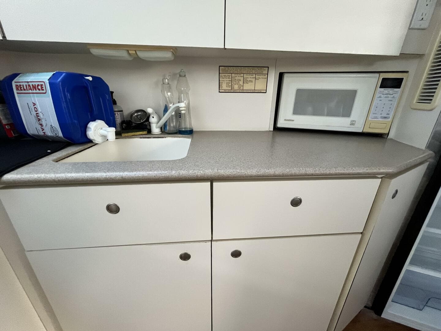 Compact kitchen area in a 1996 Silverton 372 Signature yacht with sink and microwave.