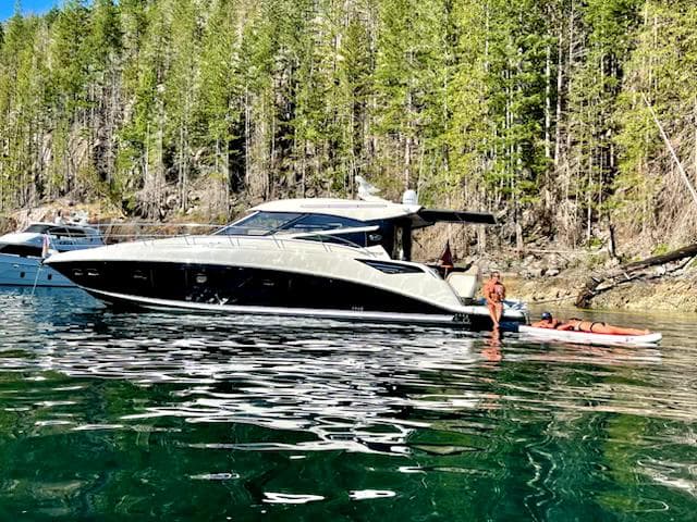 2015 Sea Ray 470 Sundancer yacht on serene water near a forested shoreline.