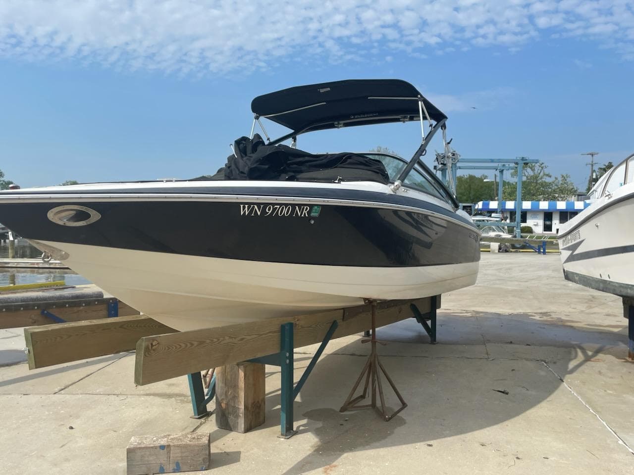 2005 Cobalt 246 boat on a stand, marina background, clear sky.