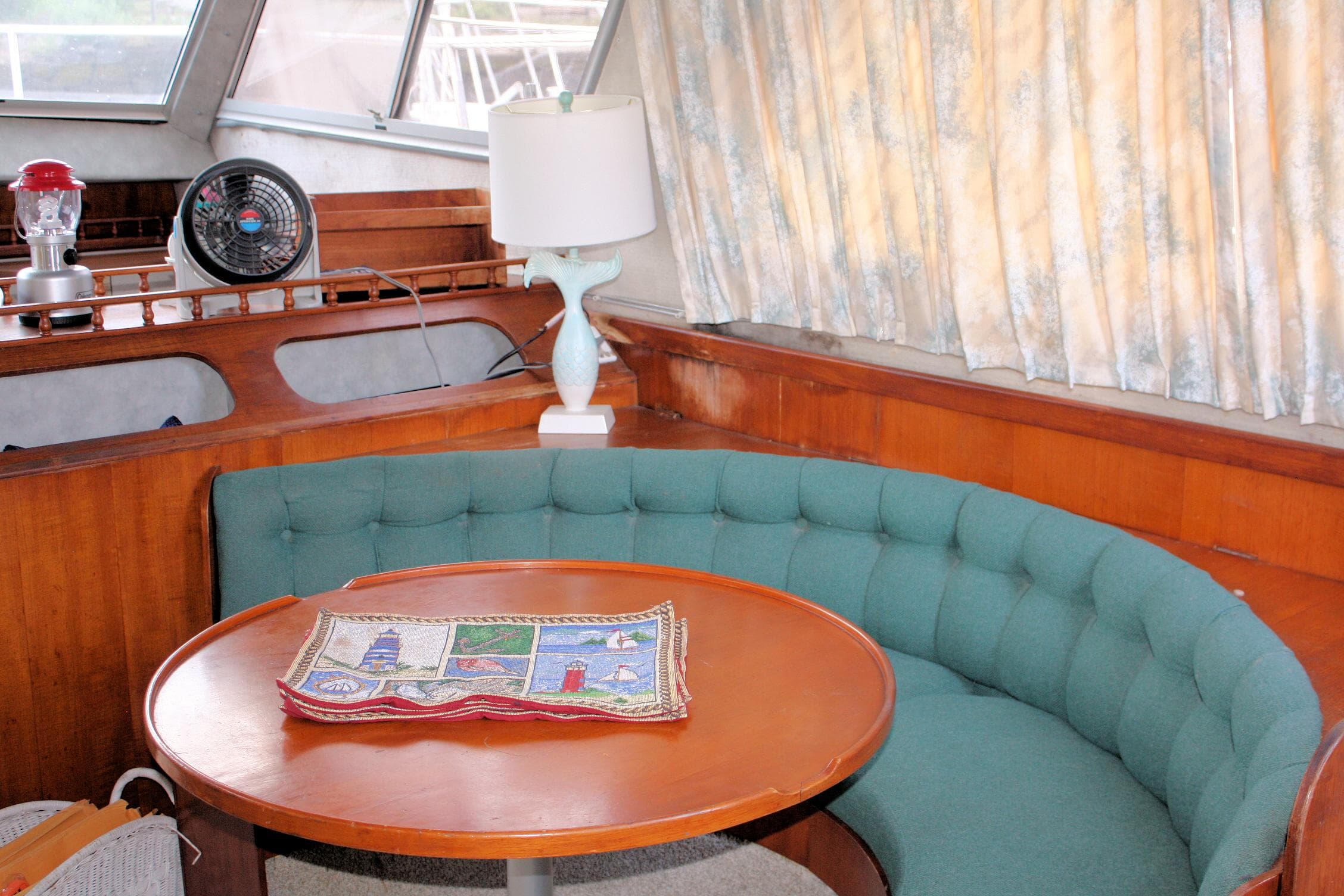 Interior of 1986 Birchwood 42 Empress yacht with round table and green seating.