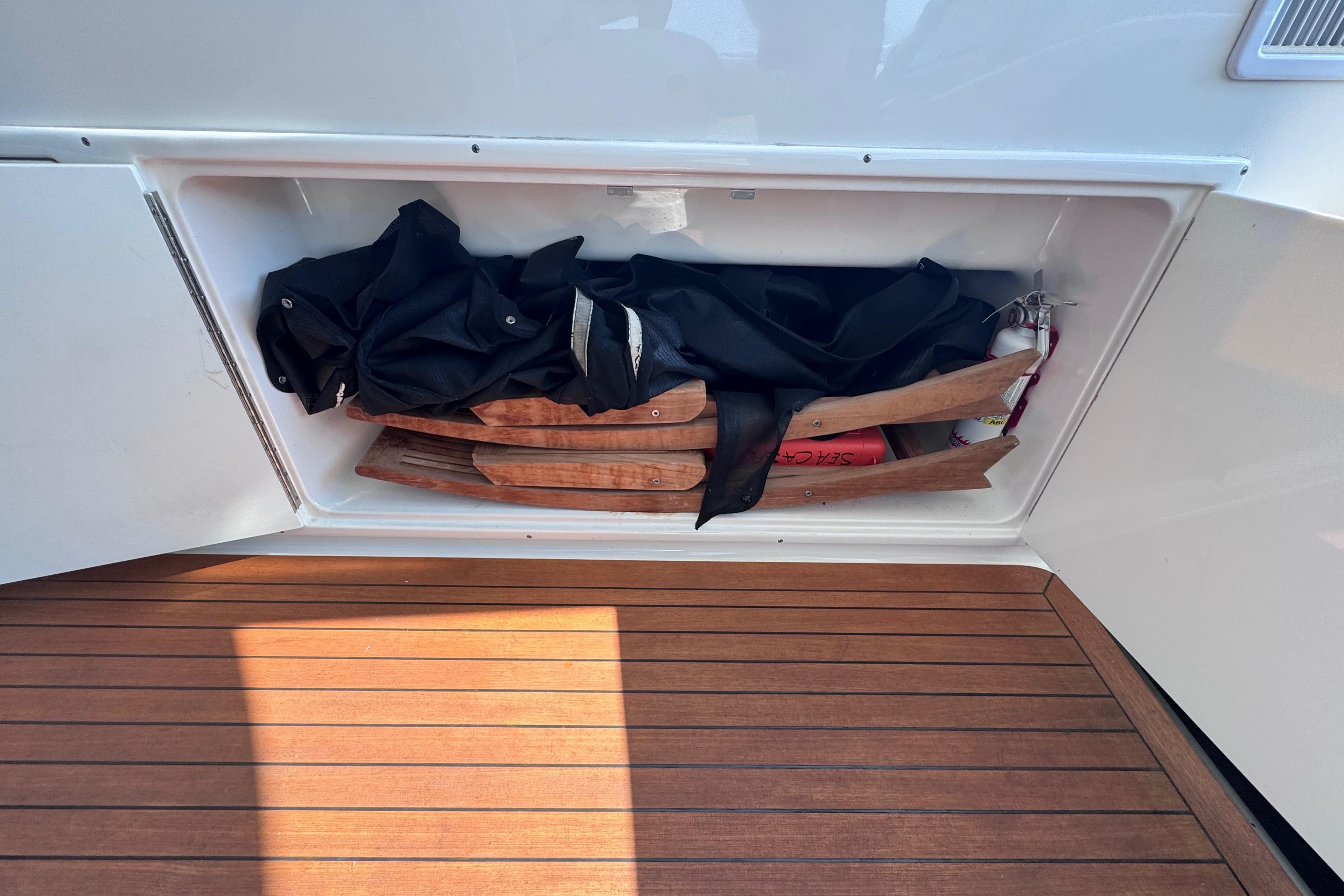 Storage compartment on 2011 Sea Ray 540 Sundancer yacht with wooden items and black fabric.