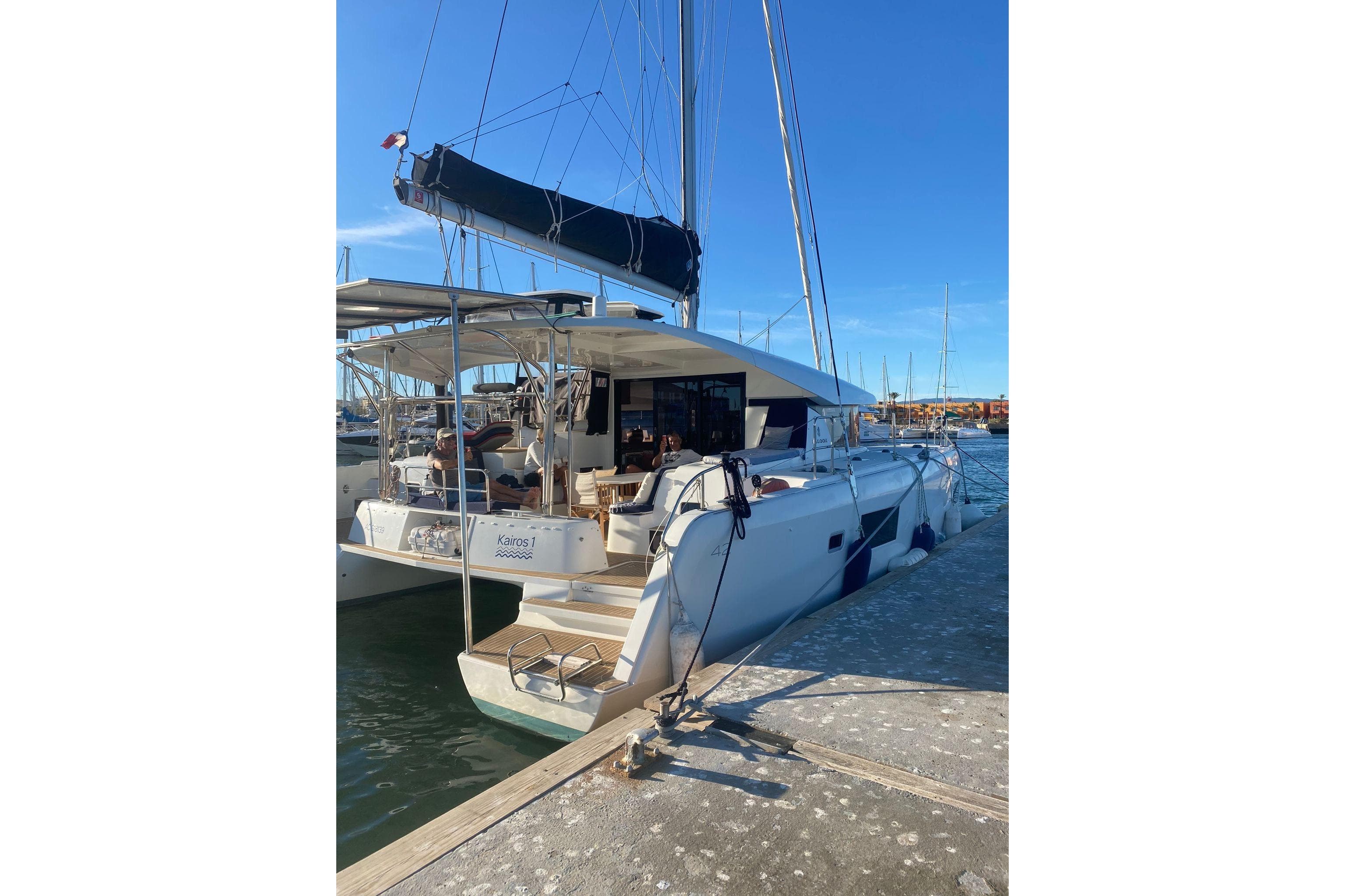 2020 Lagoon 42 catamaran docked at marina under clear blue sky.
