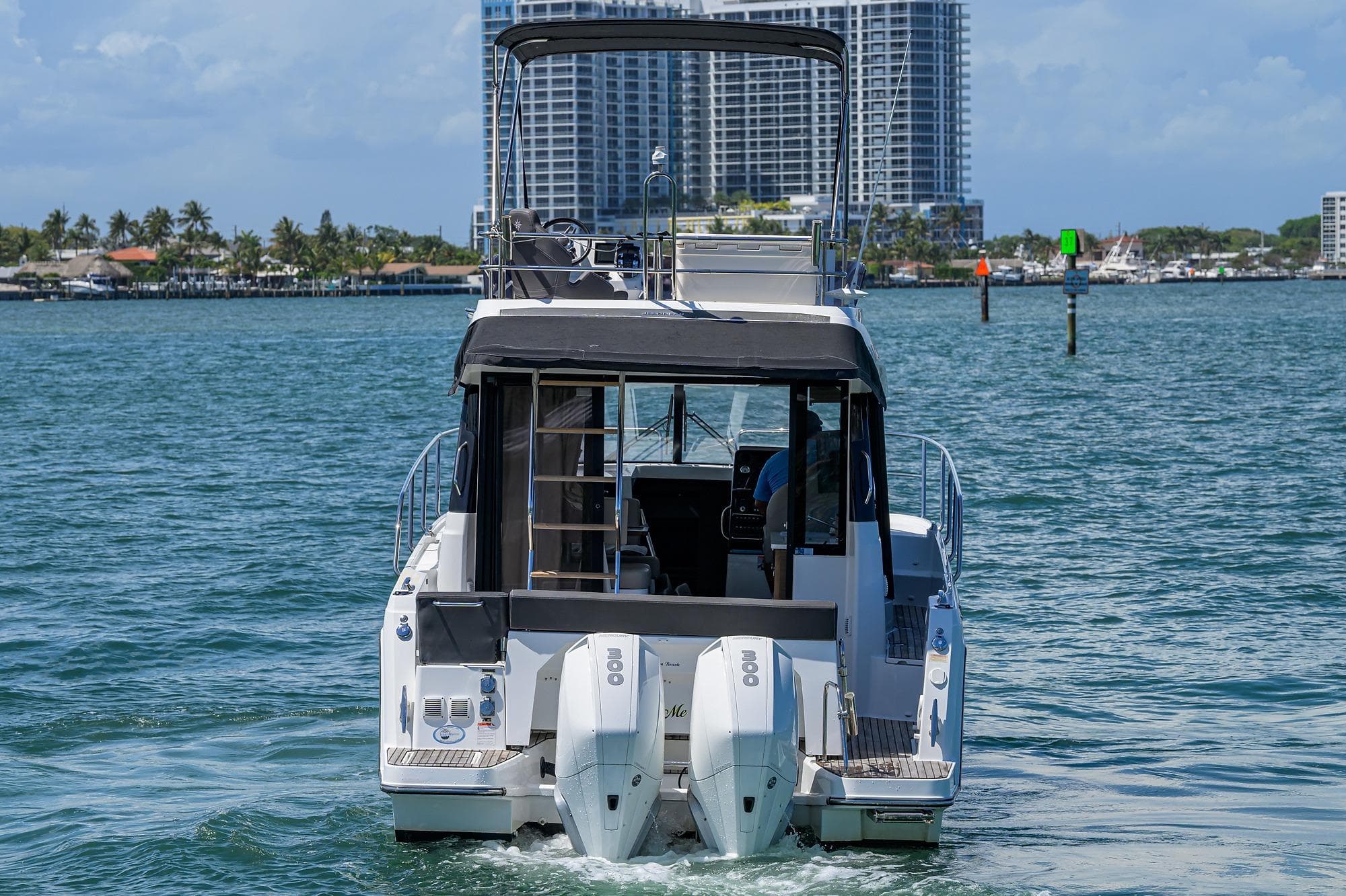 2022 Jeanneau NC Weekender 1095 Fly cruising on water with cityscape backdrop.