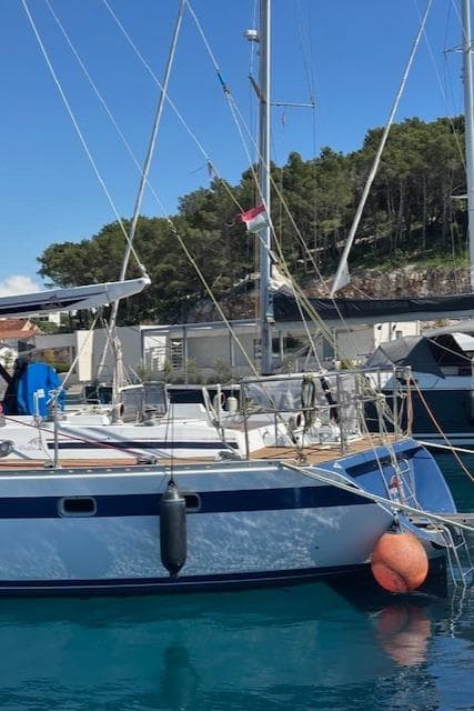 1984 Tayana 55 sailboat docked in a marina with clear blue water.