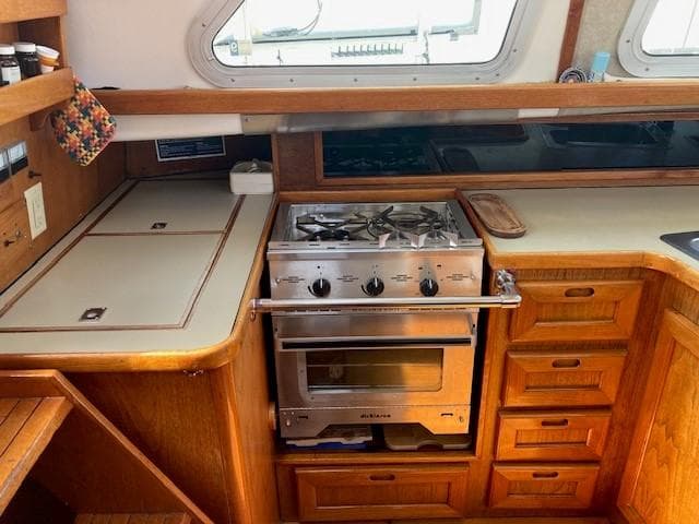 1980 Cooper 416 Pilothouse kitchen with stove, wooden cabinetry, and countertop.