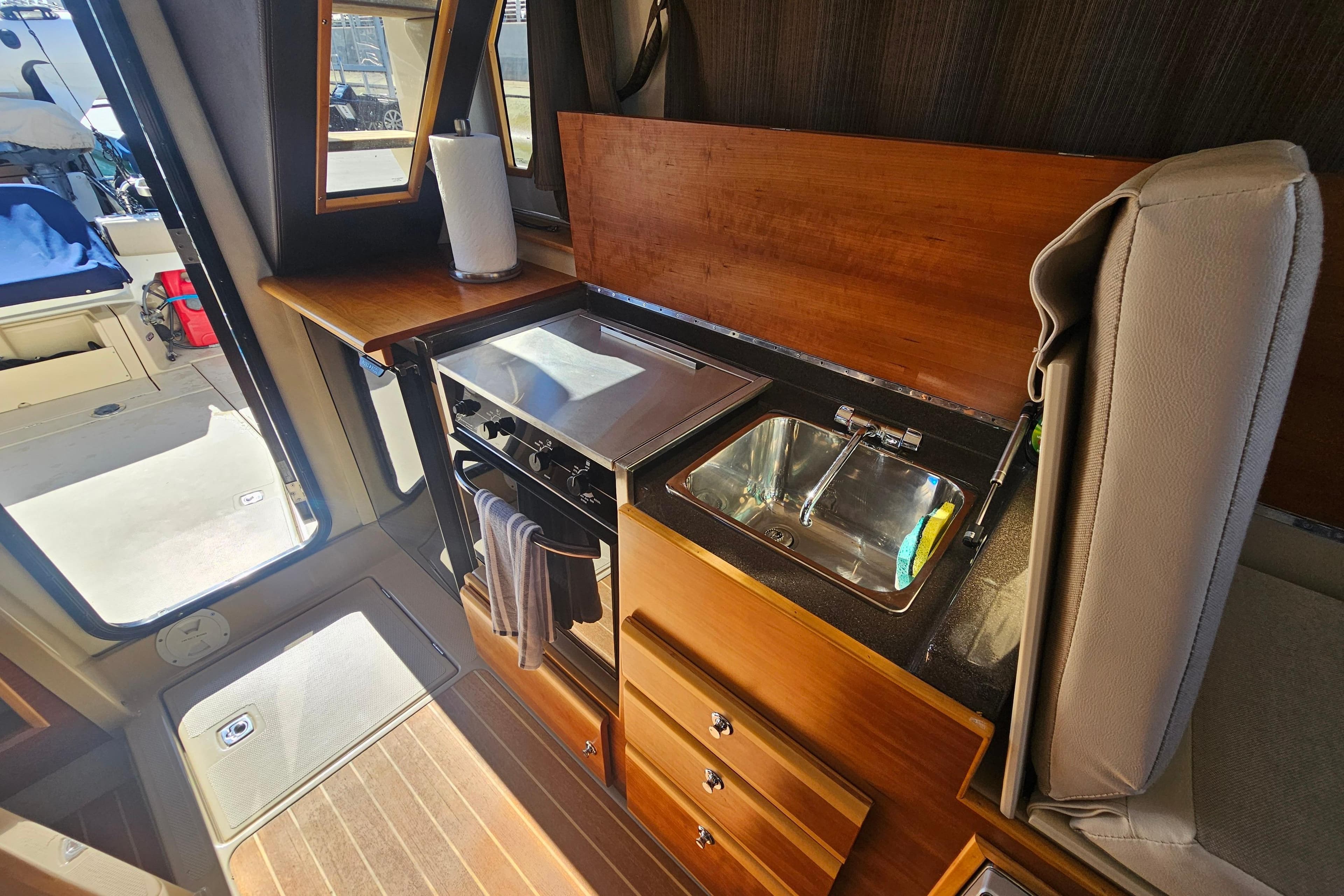 Interior of 2015 Cutwater 30 Command Bridge, featuring a compact kitchen with stove and sink.