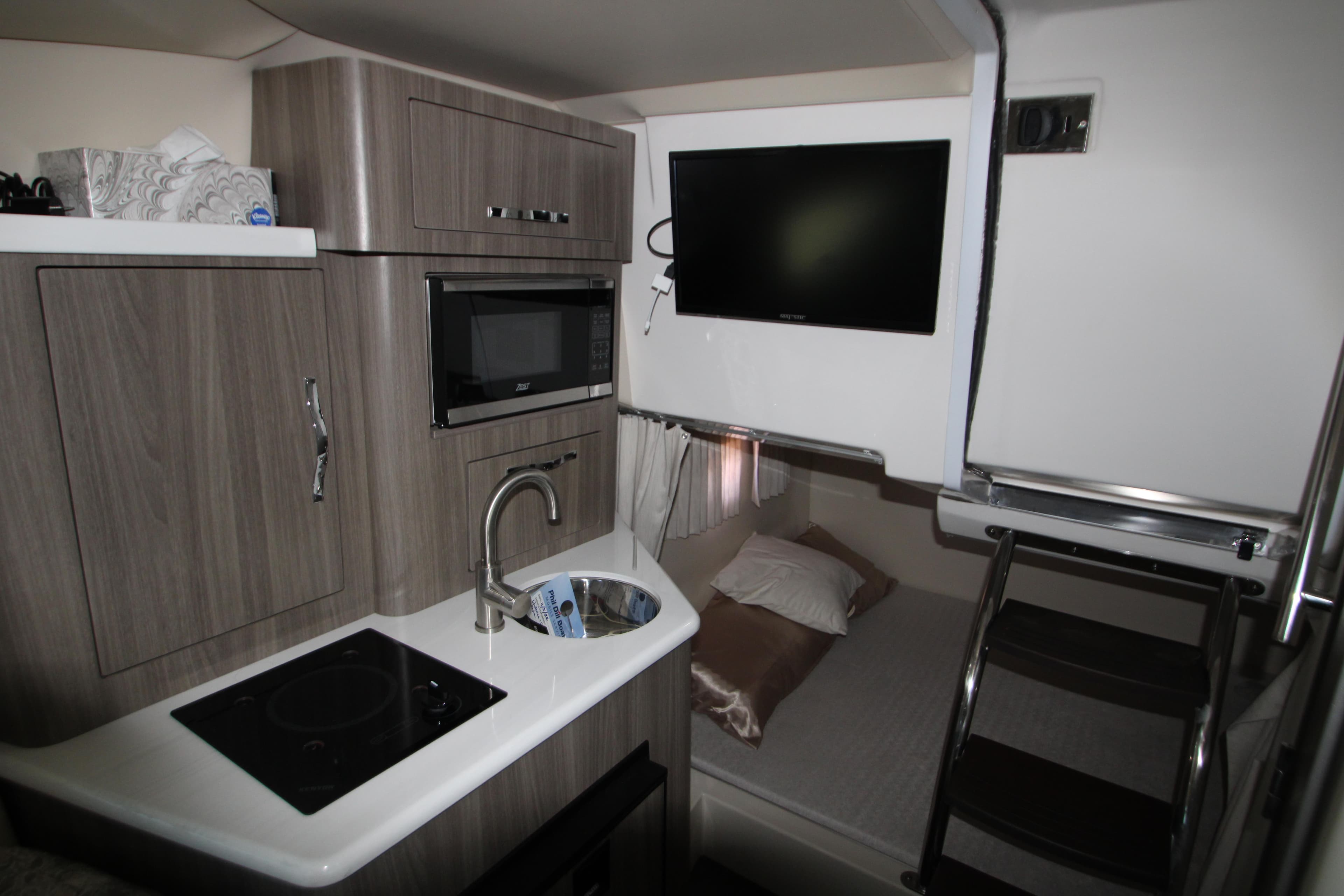 Interior of 2022 Regal 28 Express boat with kitchenette and TV.