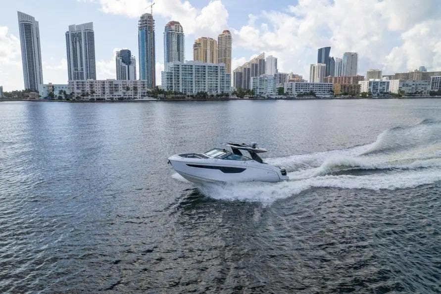 2021 Cruisers Yachts 38 GLS OB cruising near city skyline on a sunny day.