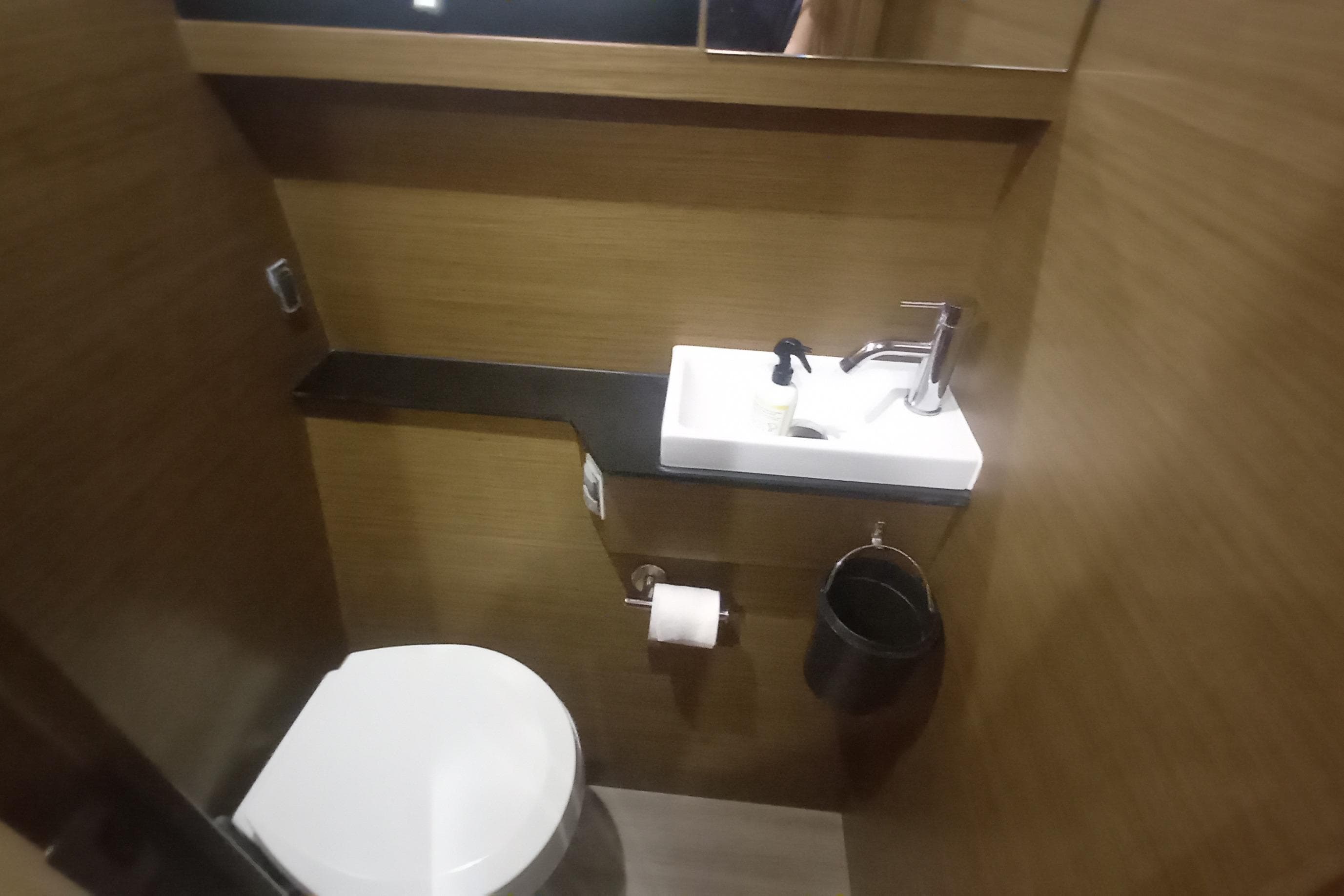 Compact bathroom in 2021 Nautitech 46 Open yacht with modern fixtures and wooden finish.