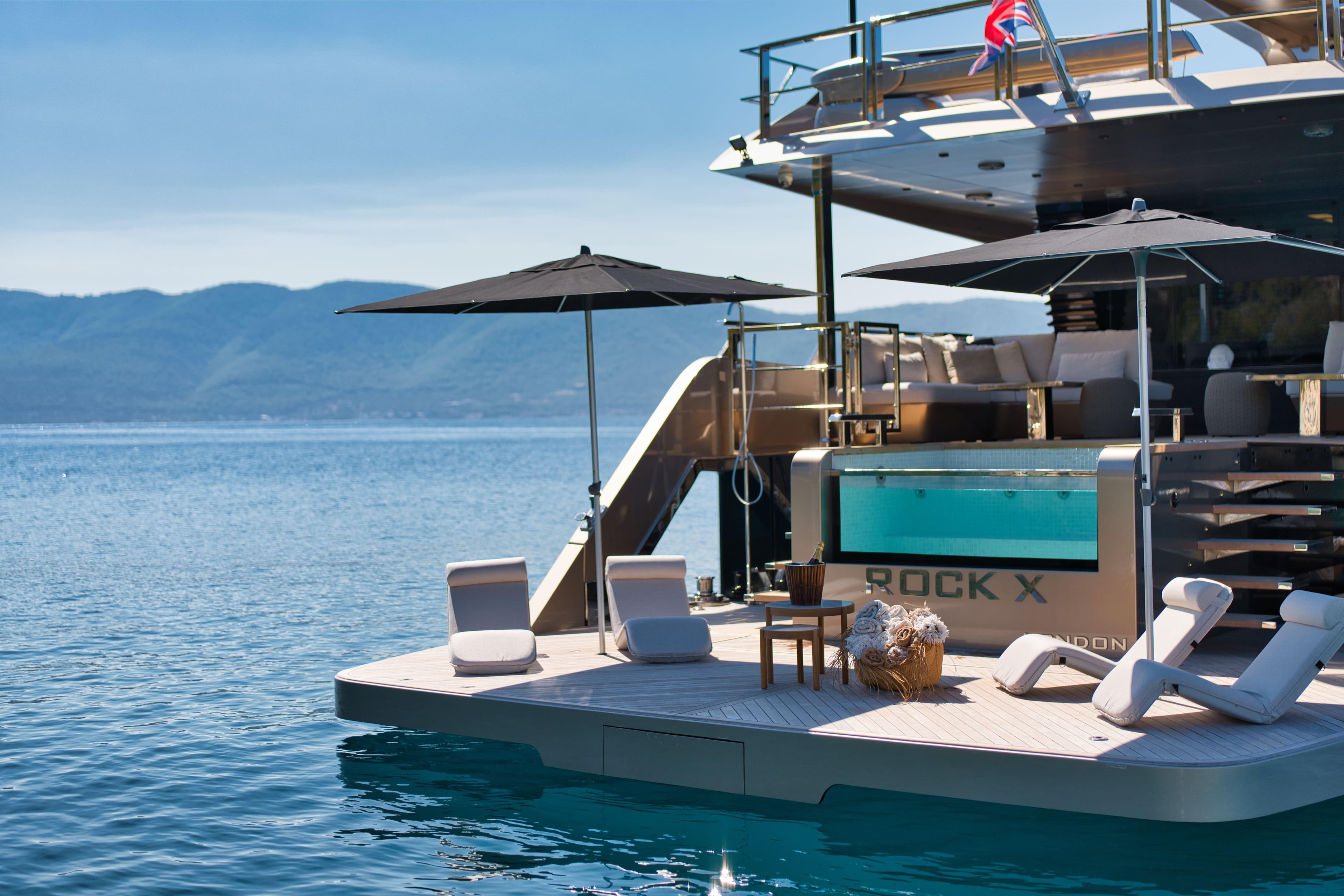 Luxurious Evadne ROCK X yacht with pool, sun loungers, and umbrellas on a serene sea.