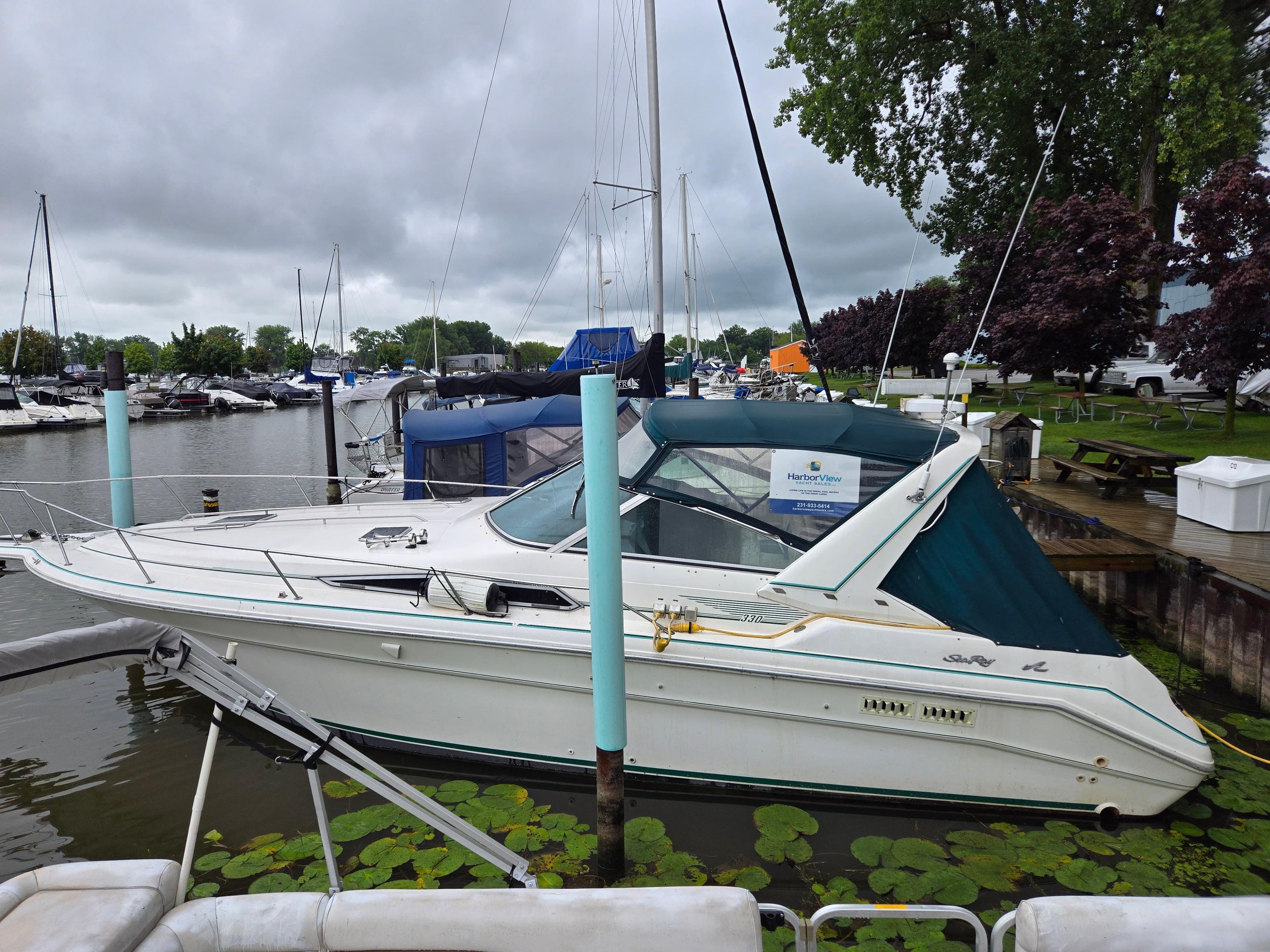 1993 Sea Ray 330 Express Cruiser docked at a marina on a cloudy day.