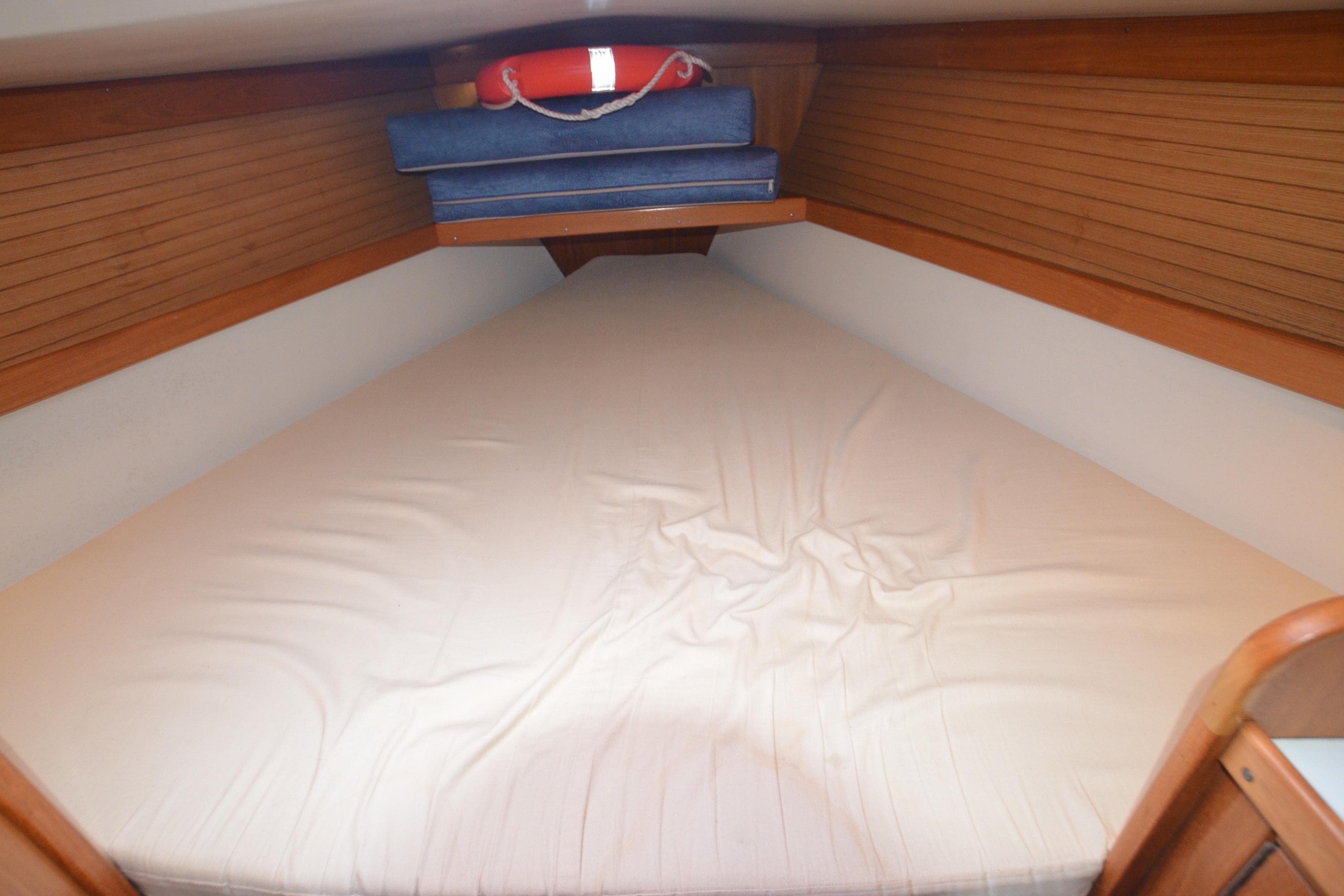 Cozy V-berth cabin in 2003 Catalina 36 MkII sailboat with wooden paneling and cushions.