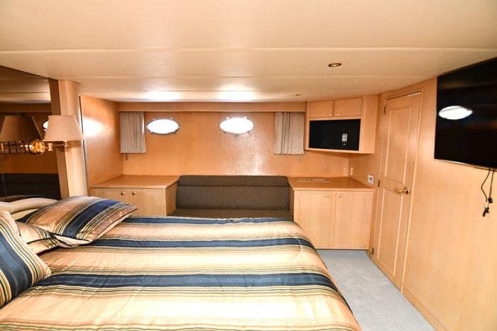 Luxurious bedroom interior of 1997 Forbes Cooper 74 Pilothouse yacht with striped bedding.