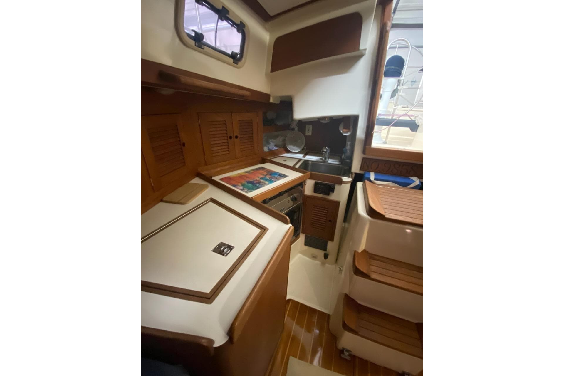 Interior of 1992 Tartan 31 Piper sailboat with wooden cabinetry and compact kitchen area.