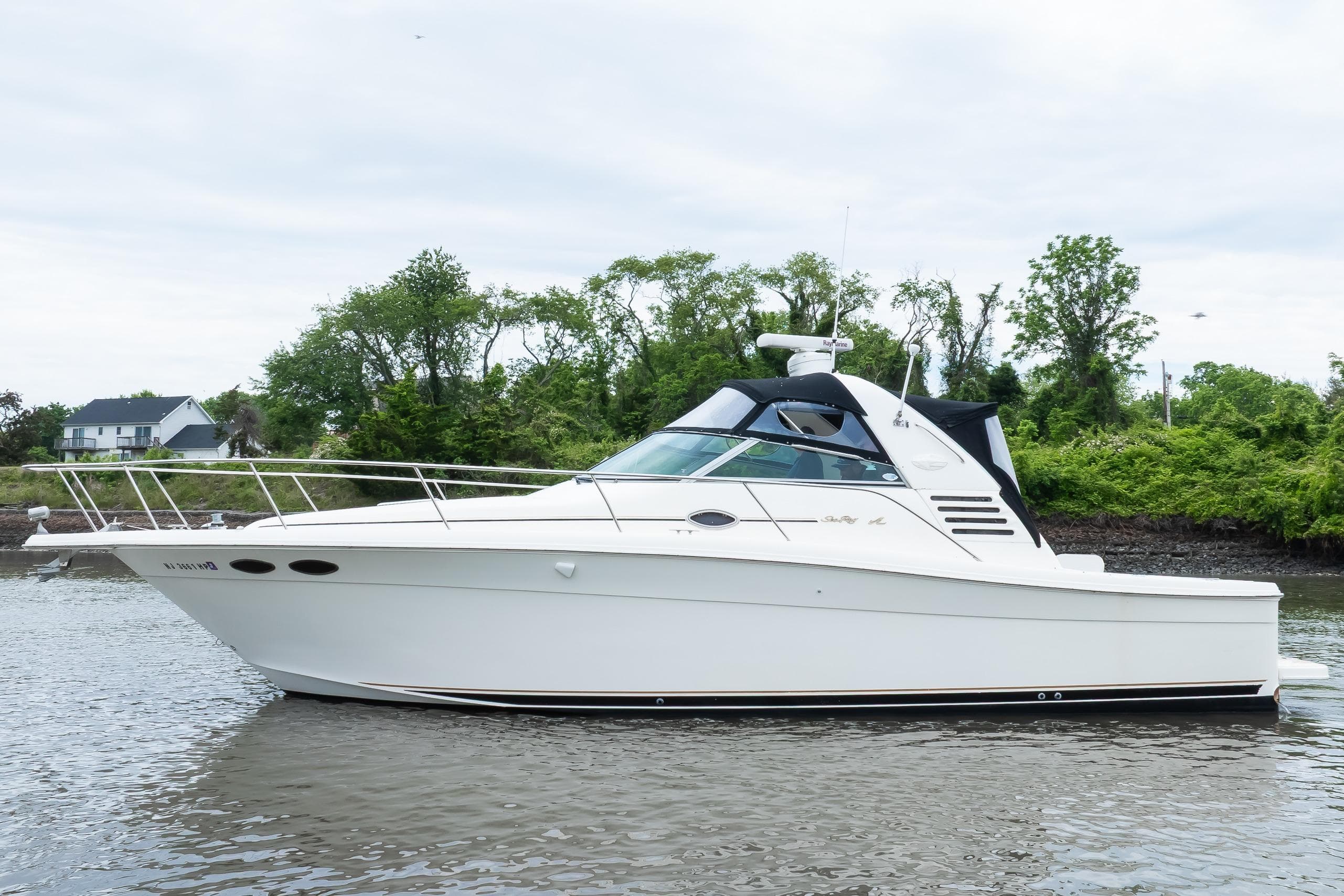1998 Sea Ray 330 Express boat on calm water with lush green background.