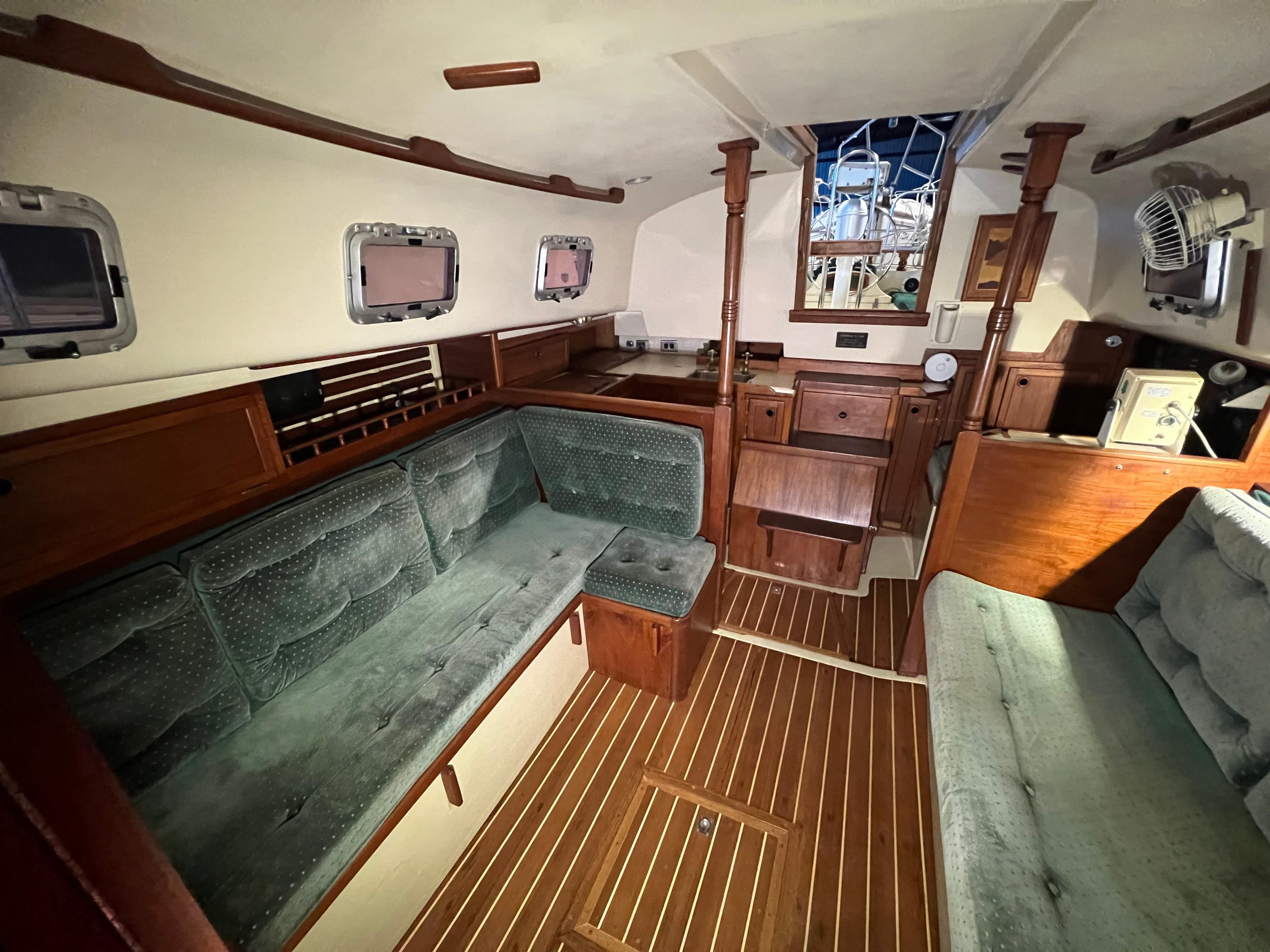Interior of 1987 Bayfield 32C sailboat with wooden furnishings and green upholstery.