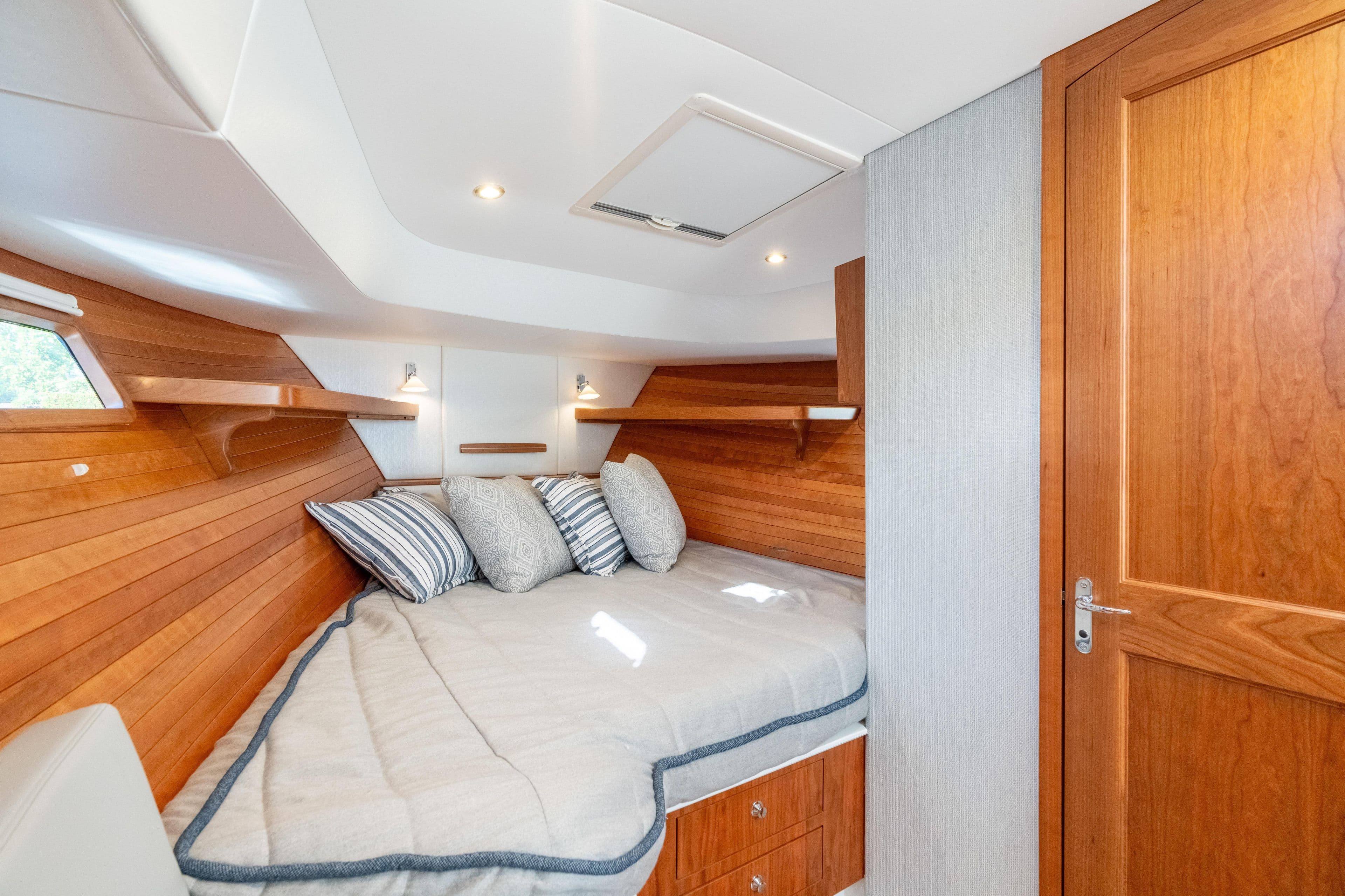 Luxurious cabin interior of 2026 MJM 38RS yacht with wooden accents and cozy bedding.