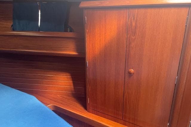 Interior of 2002 Jeanneau Sun Odyssey 45.2 yacht with wooden cabinetry and blue upholstery.