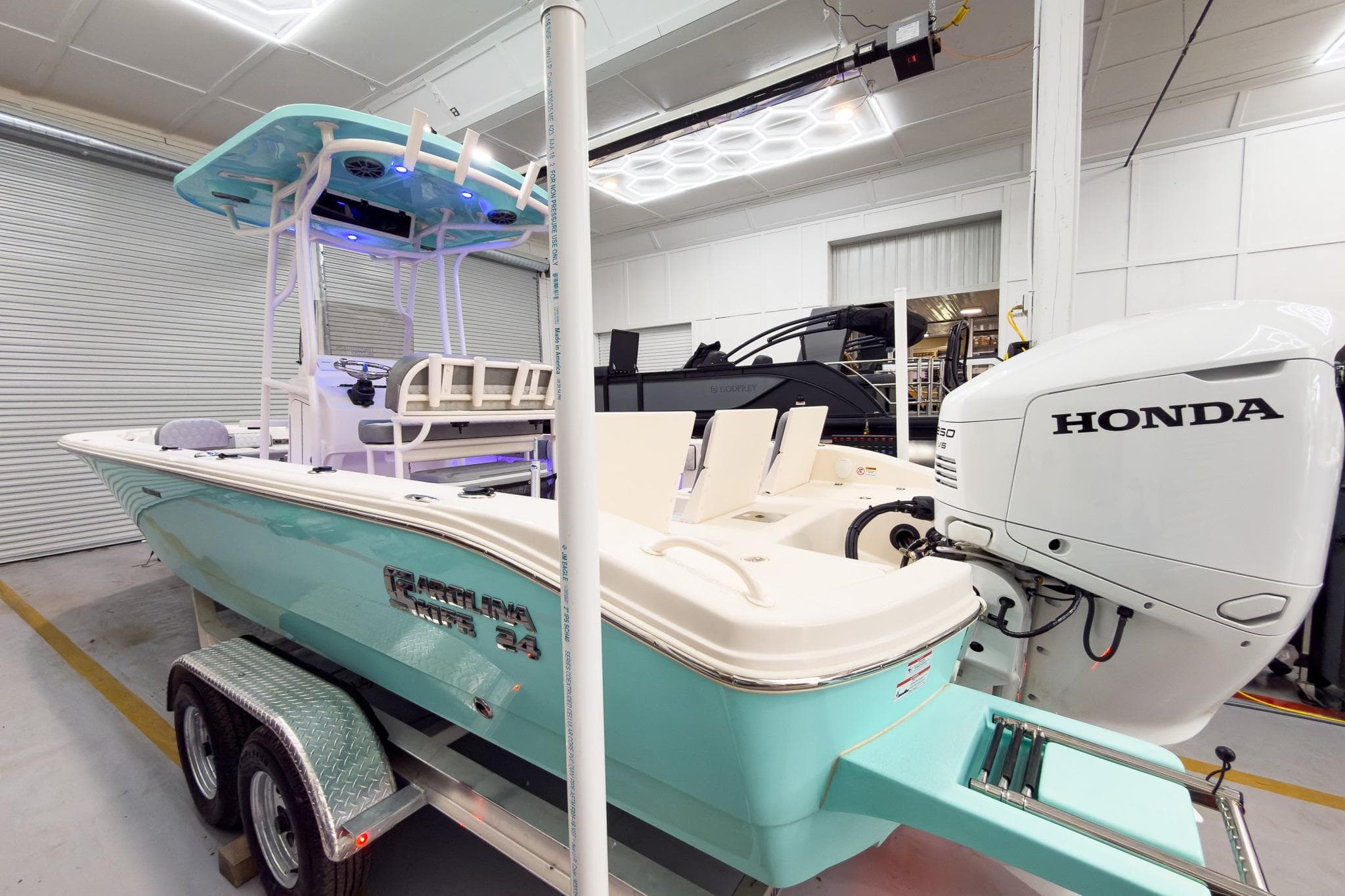 2026 Carolina Skiff 24 Ultra Elite boat with Honda engine in a workshop.