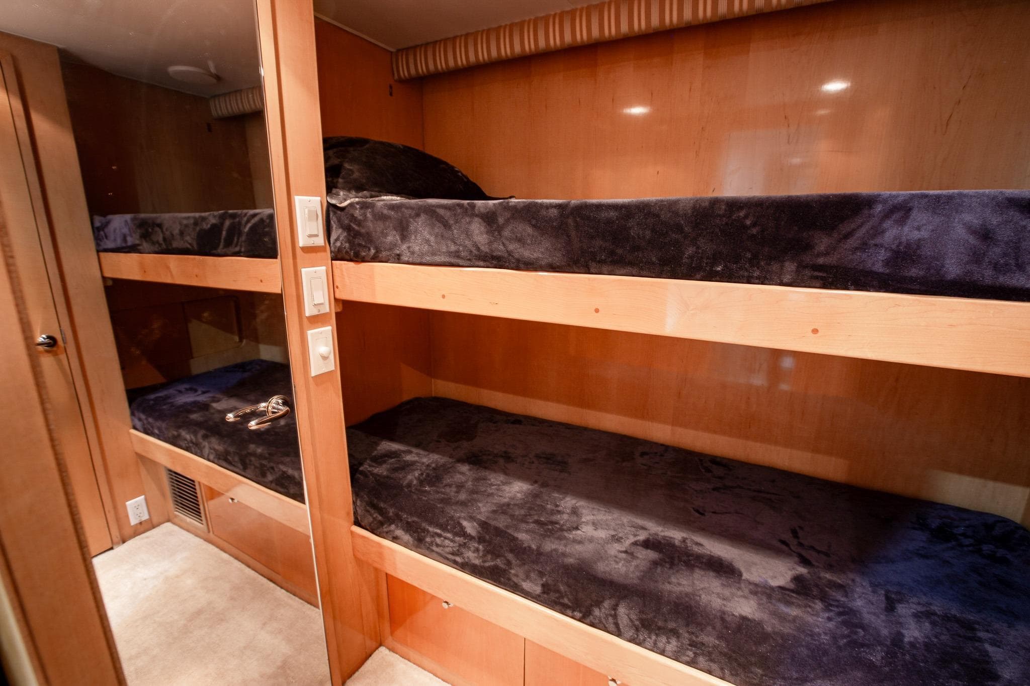 Bunk beds in 2001 Hatteras 75 Cockpit Motor Yacht cabin, featuring plush bedding and wood paneling.