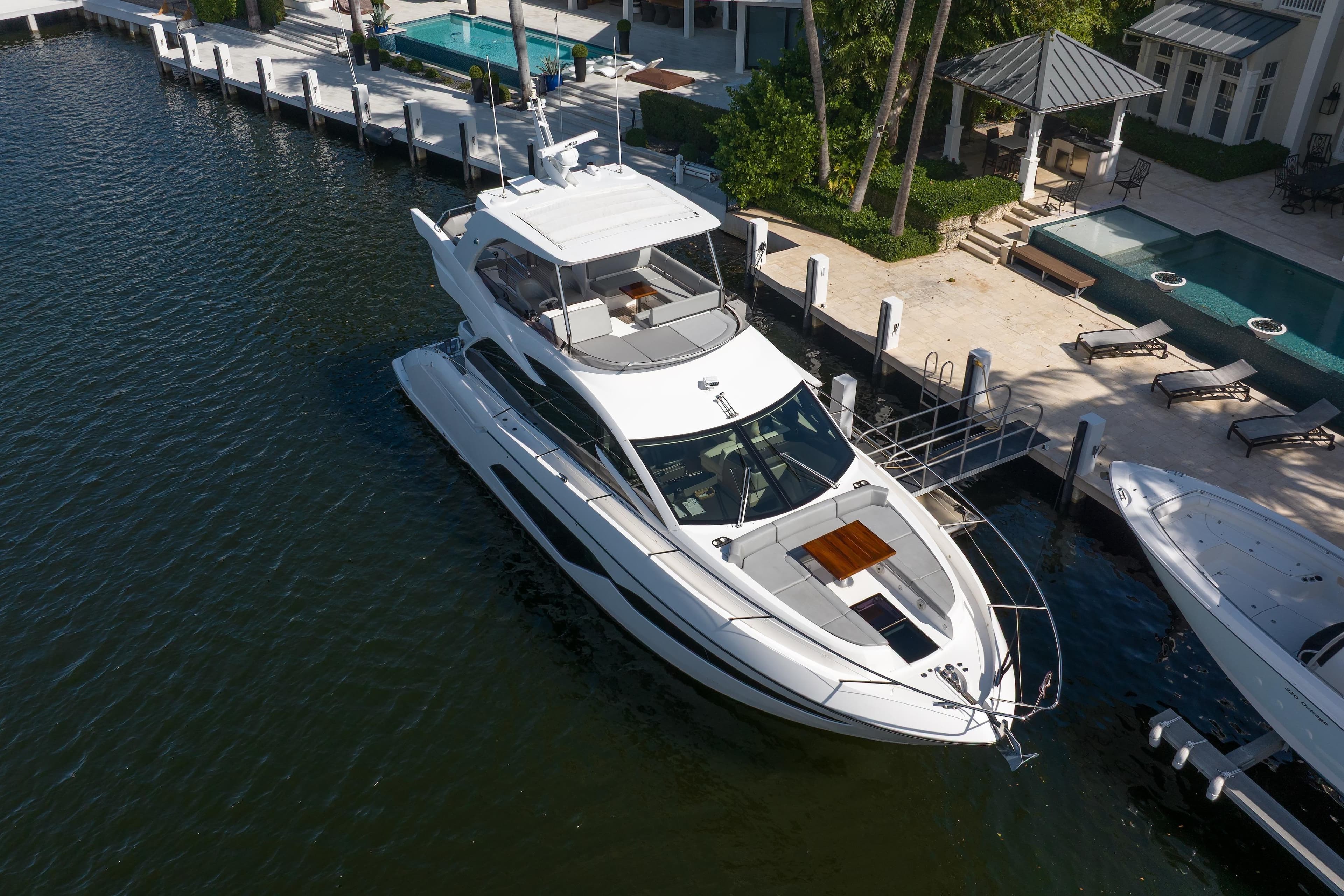 2020 Sunseeker Manhattan 52 yacht docked by luxury waterfront property.