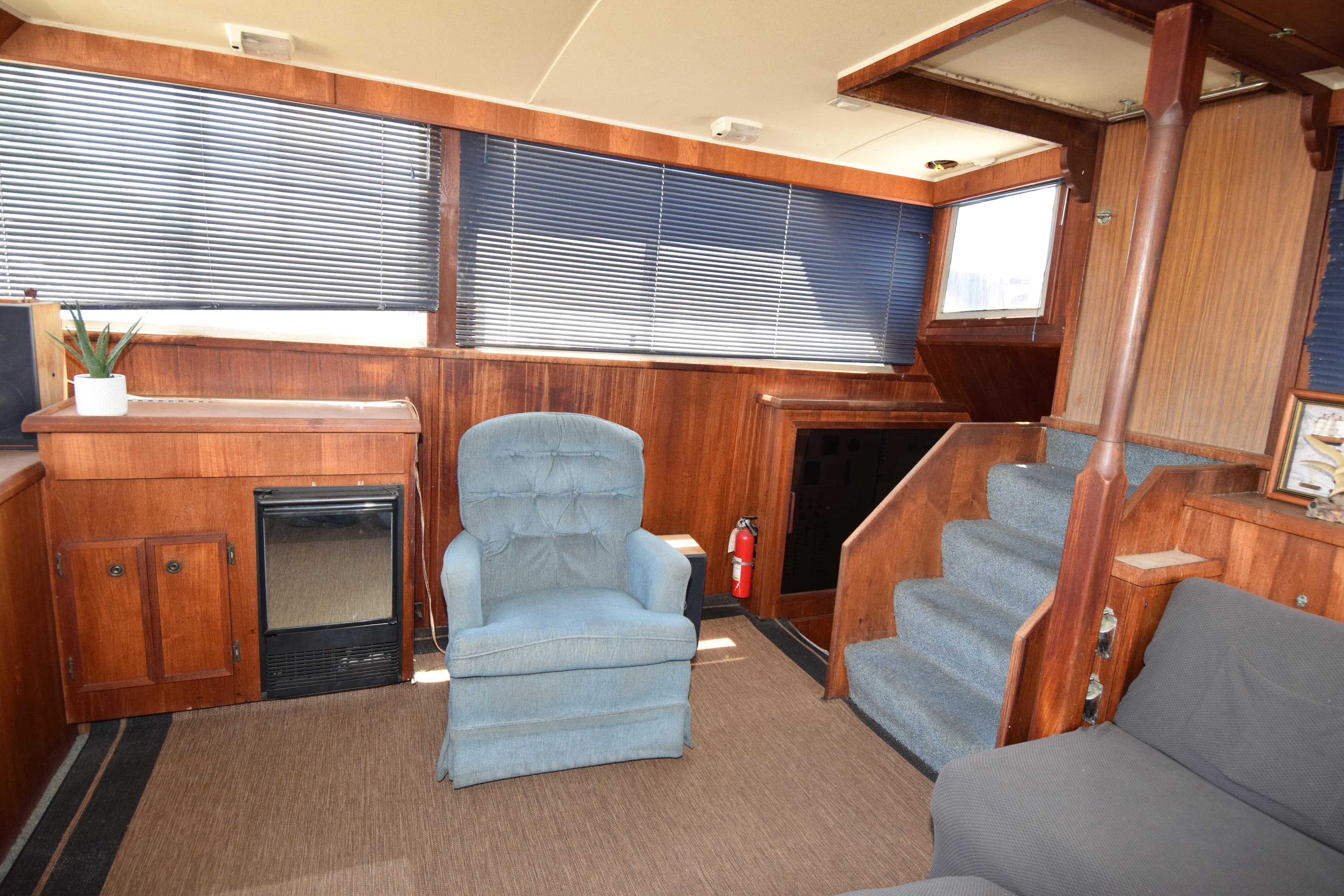 1977 Uniflite 42 Double Cabin interior with blue chair, wood paneling, and stairs.