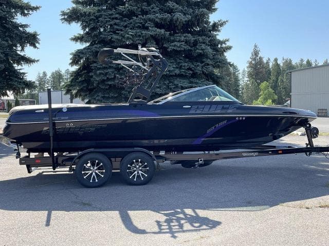 2023 Sanger V237 SX boat on trailer, black with purple accents, parked outdoors.