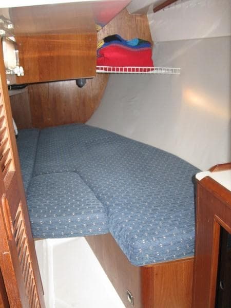 1986 Hunter 34 sailboat cabin with blue cushioned bed and wooden interior.