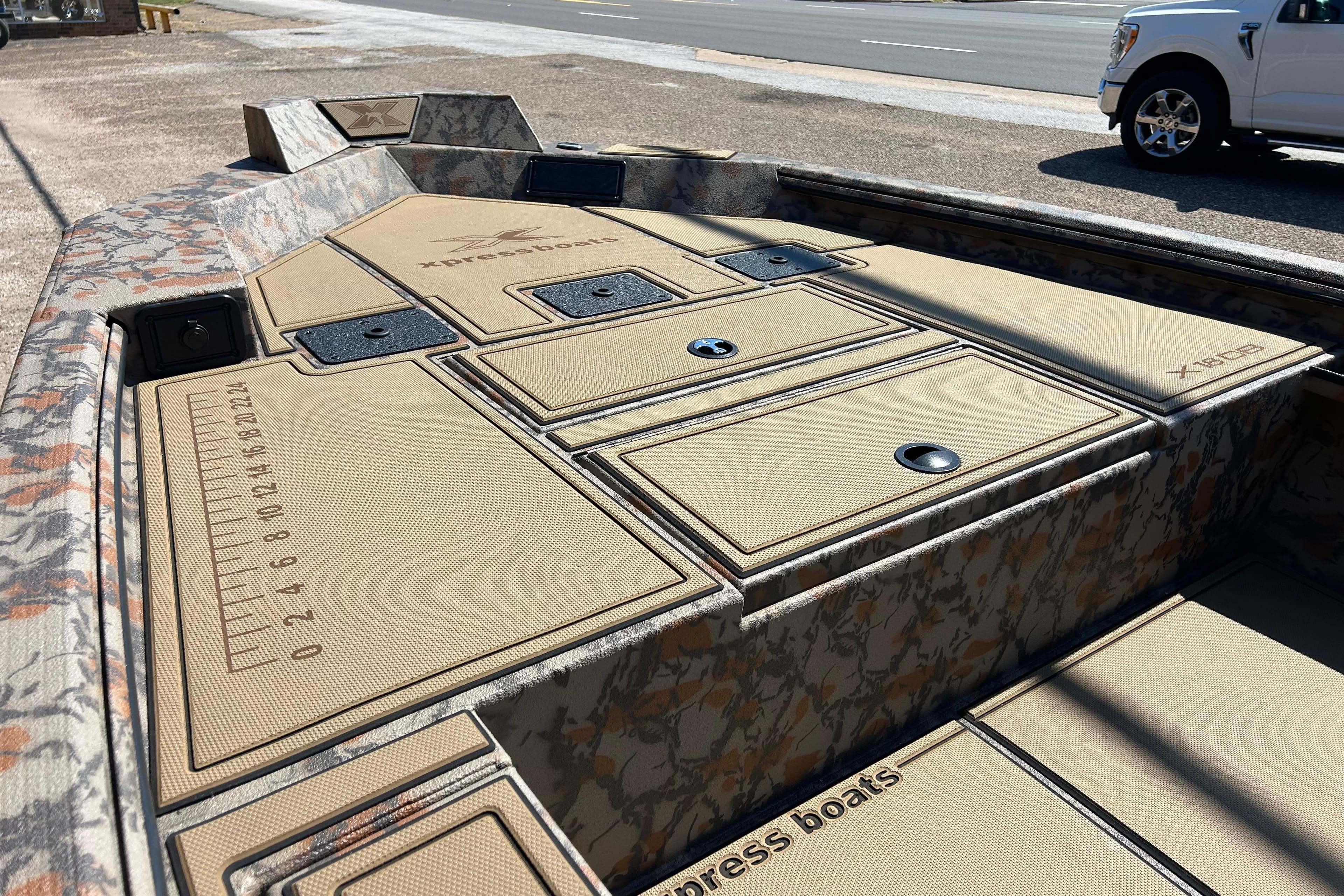 2026 Xpress X18DB boat deck with storage compartments and camouflage design.