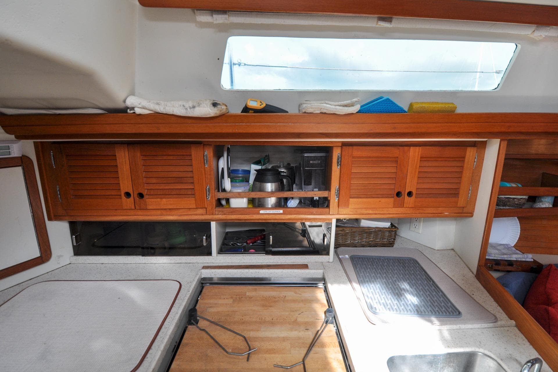 Interior of a 1993 Catalina 42 sailboat kitchen with wooden cabinets and countertop.