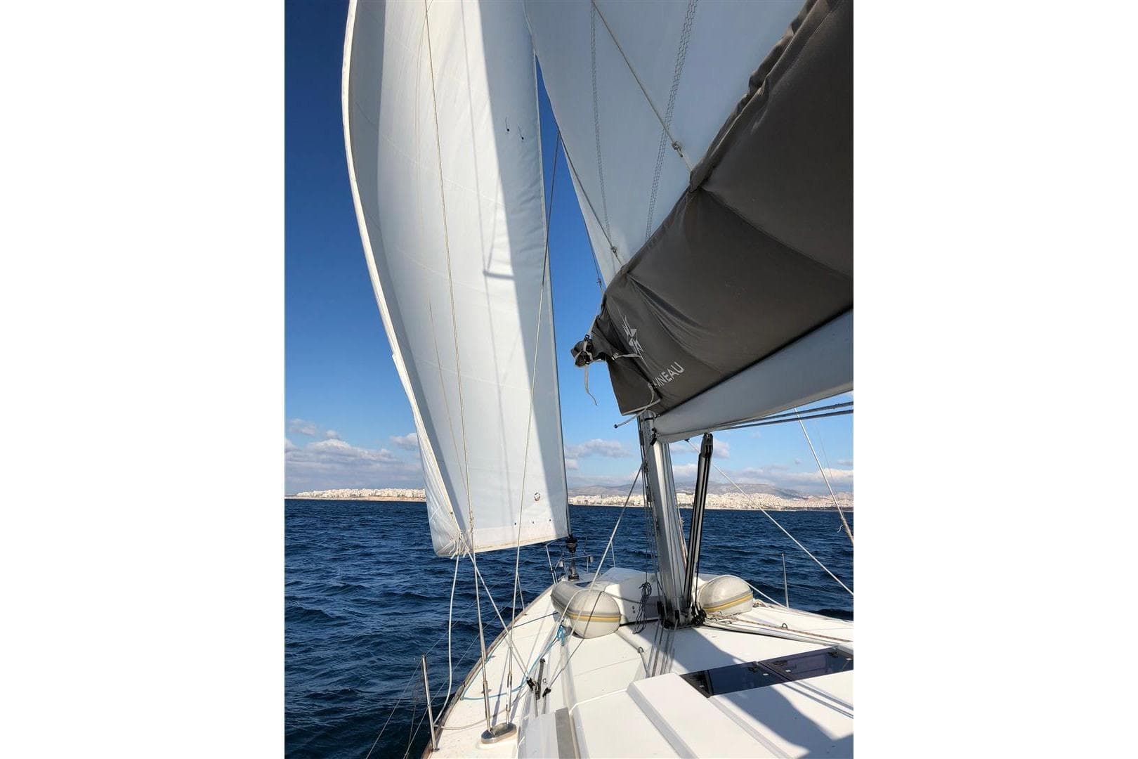 2016 Jeanneau Sun Odyssey 519 sailing on open sea under clear blue skies.