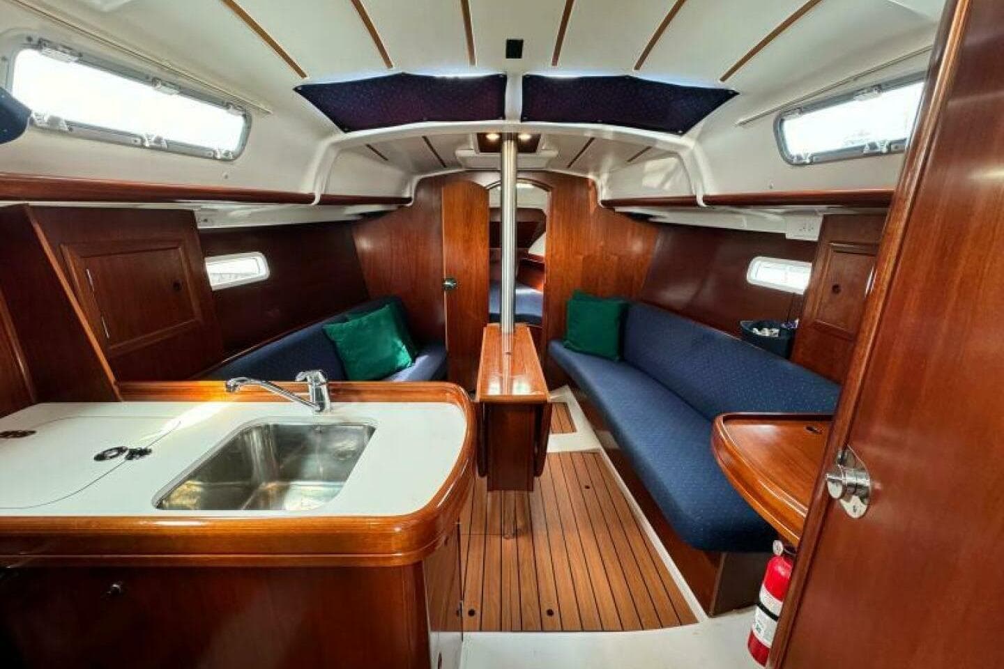 Interior of 2004 Beneteau 323 sailboat with wood finish and compact kitchen area.