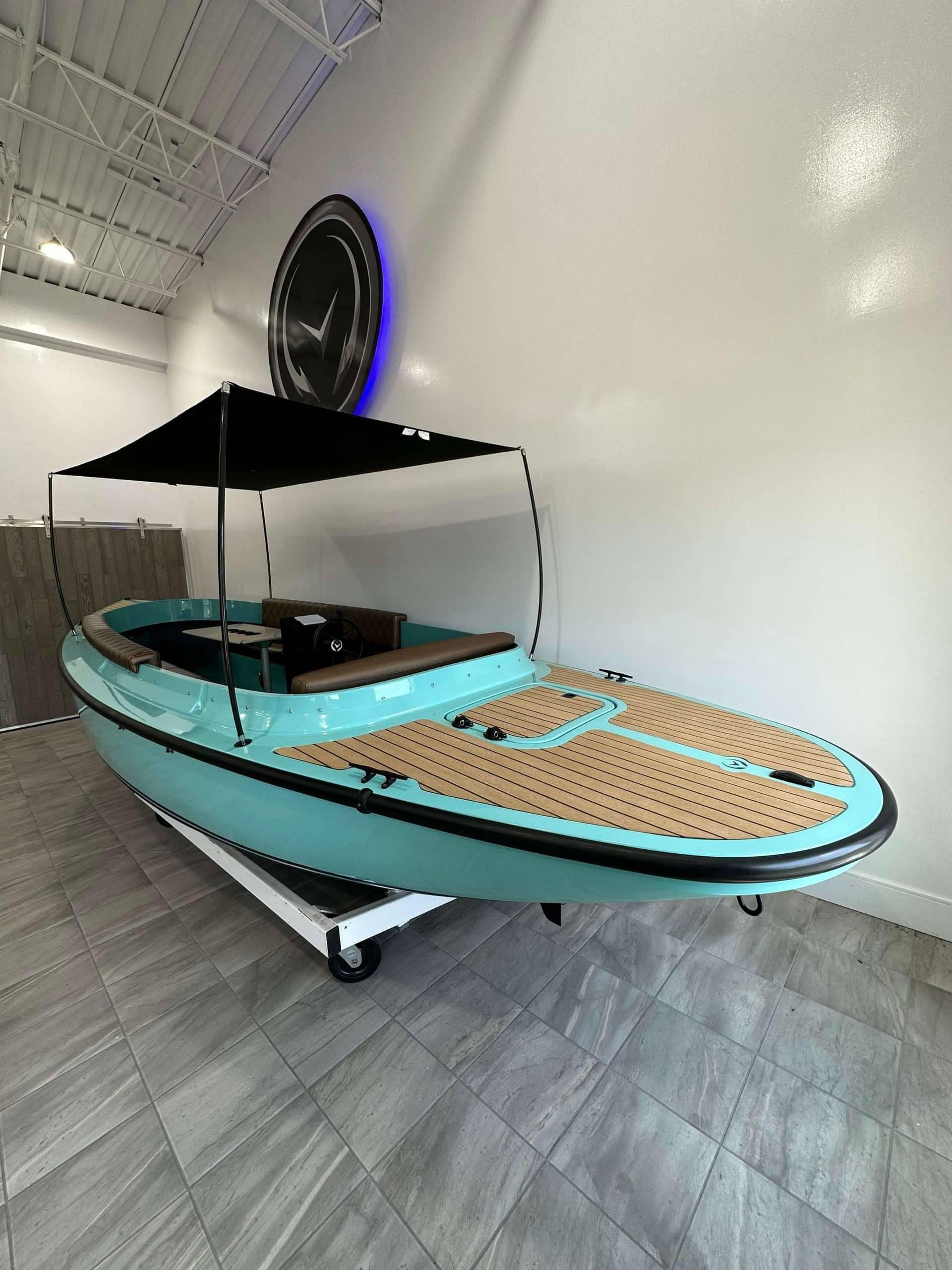 2023 Vision Marine Technologies Fantail 217 boat with canopy, displayed indoors on tiled floor.