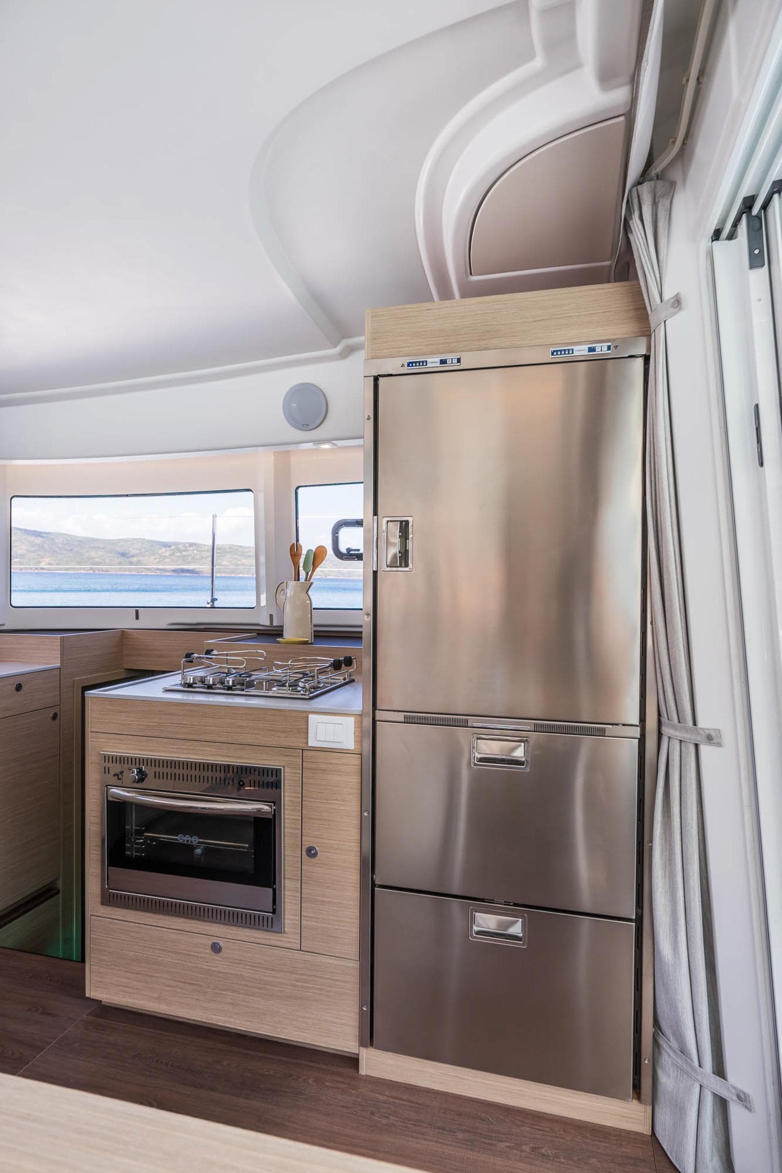 Modern kitchen interior of 2025 Lagoon 38 yacht with stainless steel appliances.