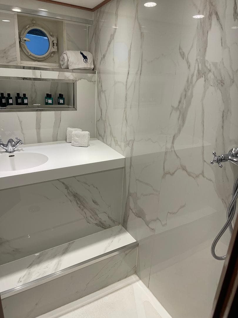 Luxurious yacht bathroom with marble walls, porthole window, and elegant fixtures, De Vries Lentsch 2300.