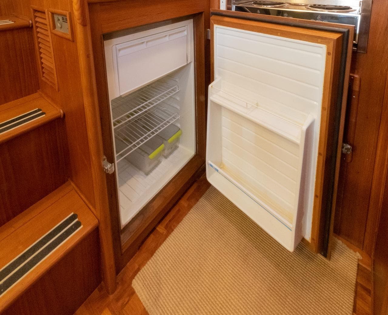Open refrigerator inside 1998 Grand Banks 38 Eastbay EX yacht, showcasing wooden interior design.