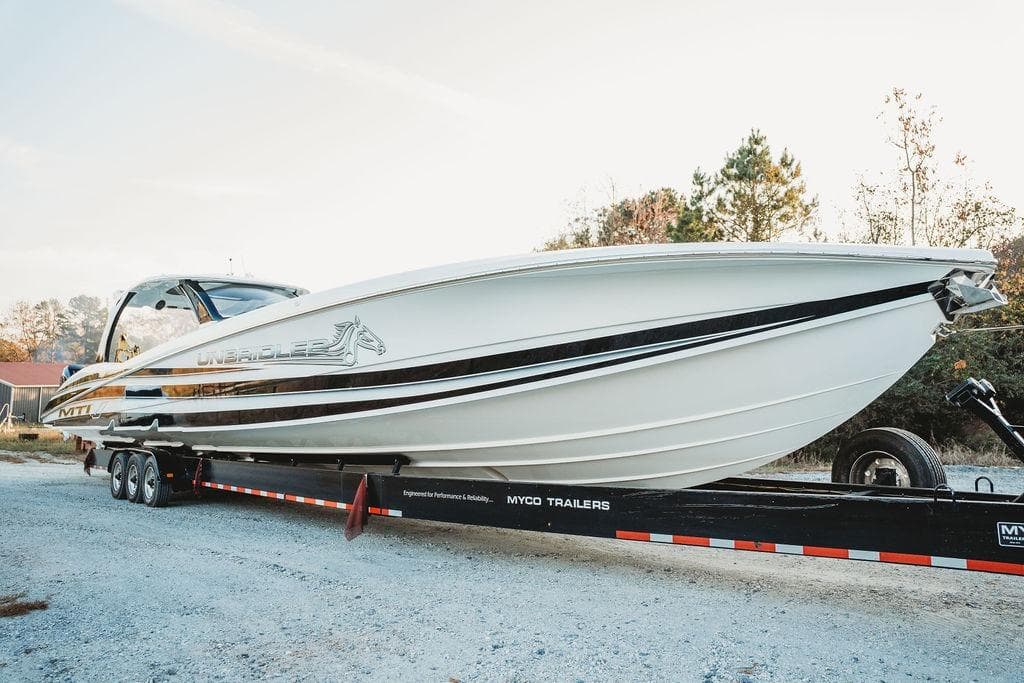 2018 MTI 57 boat on trailer, sleek design, parked outdoors.
