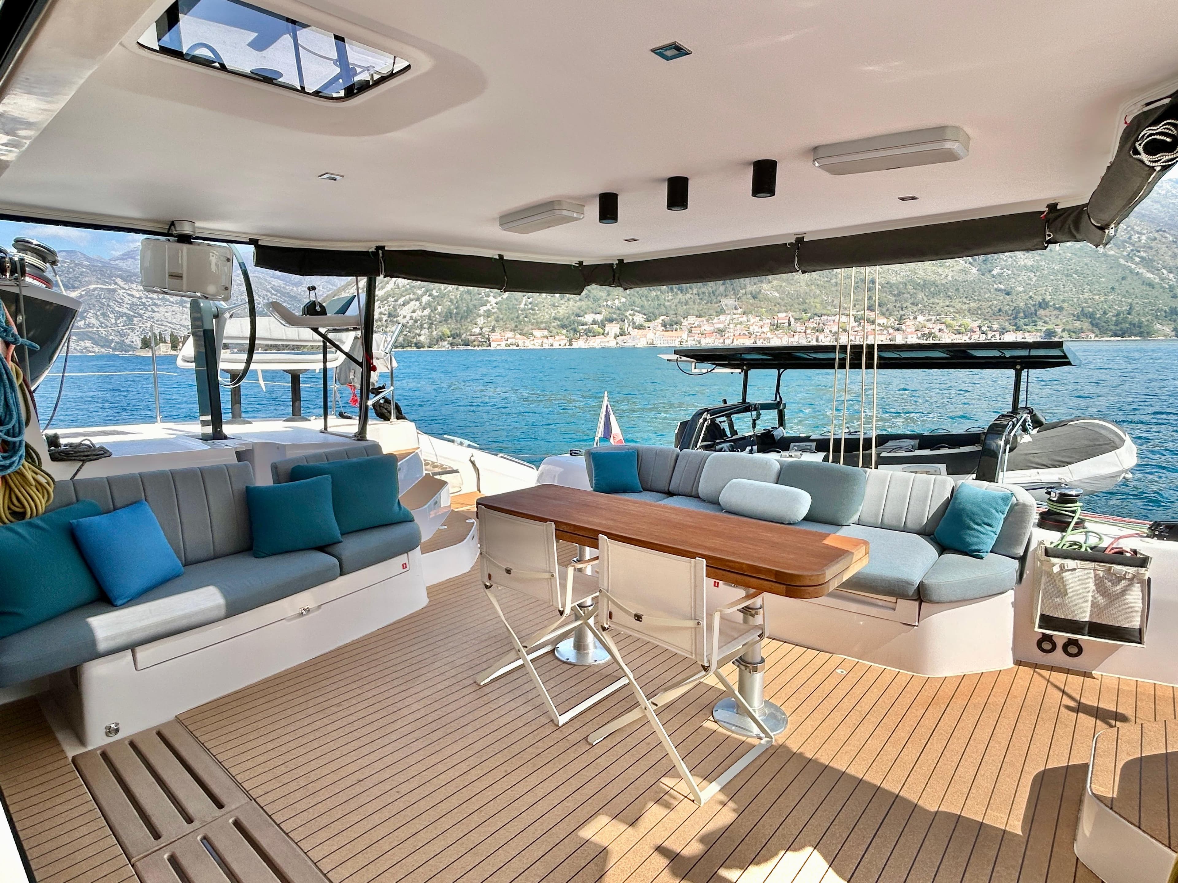 Luxurious 2022 Outremer 55 yacht deck with seating, table, and scenic ocean view.
