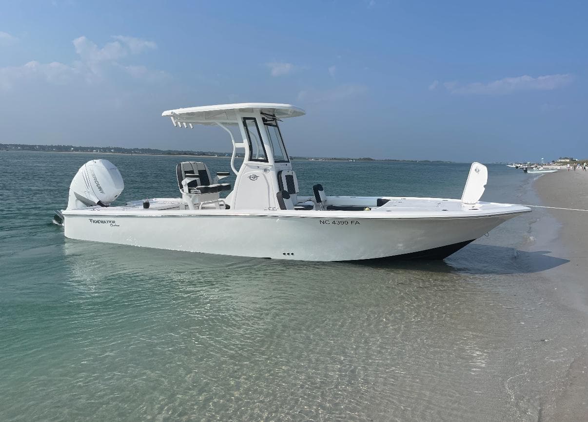 2023 Tidewater 2500CB boat anchored on a sandy beach with clear blue water.