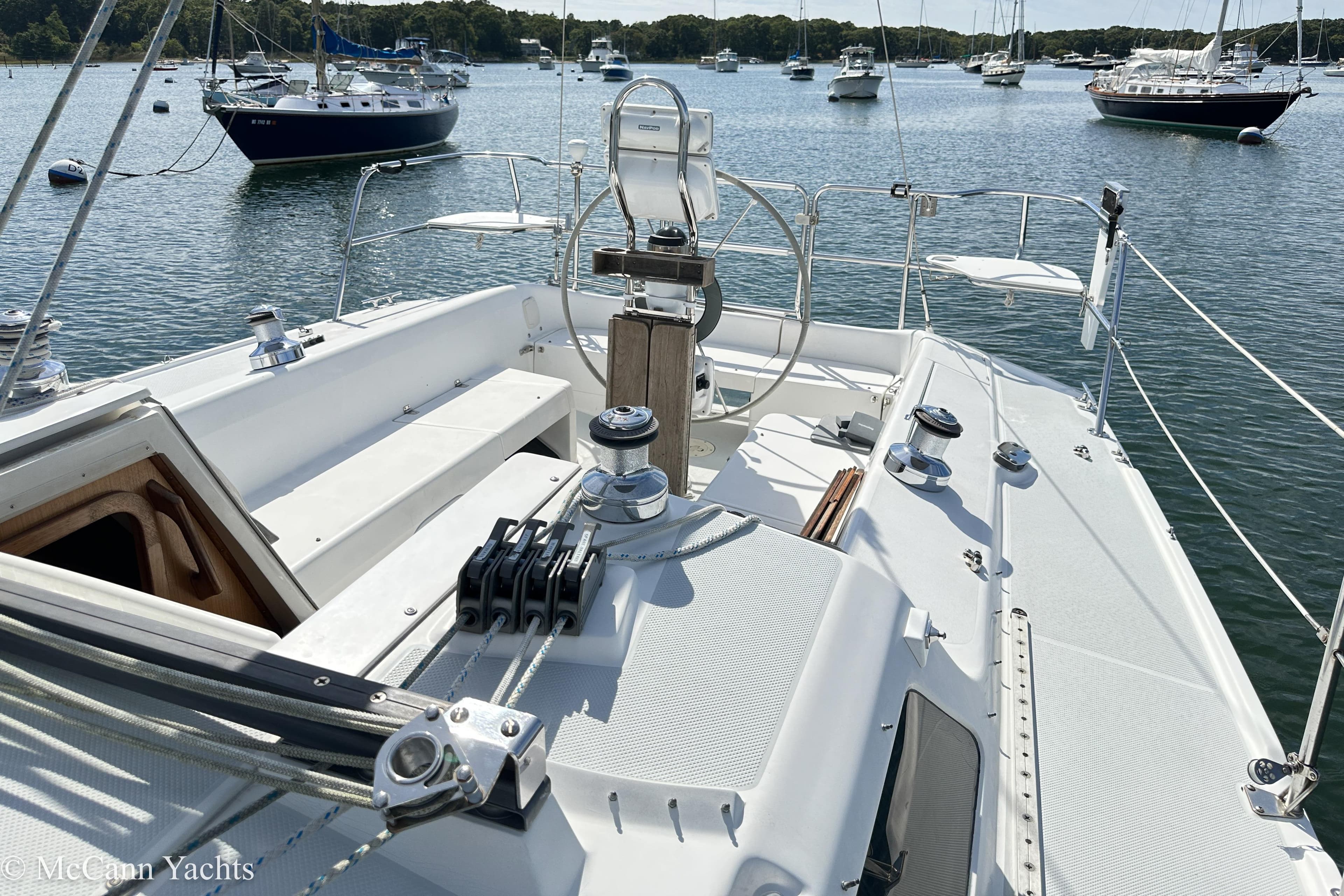 2003 Catalina 320 sailboat cockpit with steering wheel, moored in a scenic harbor.