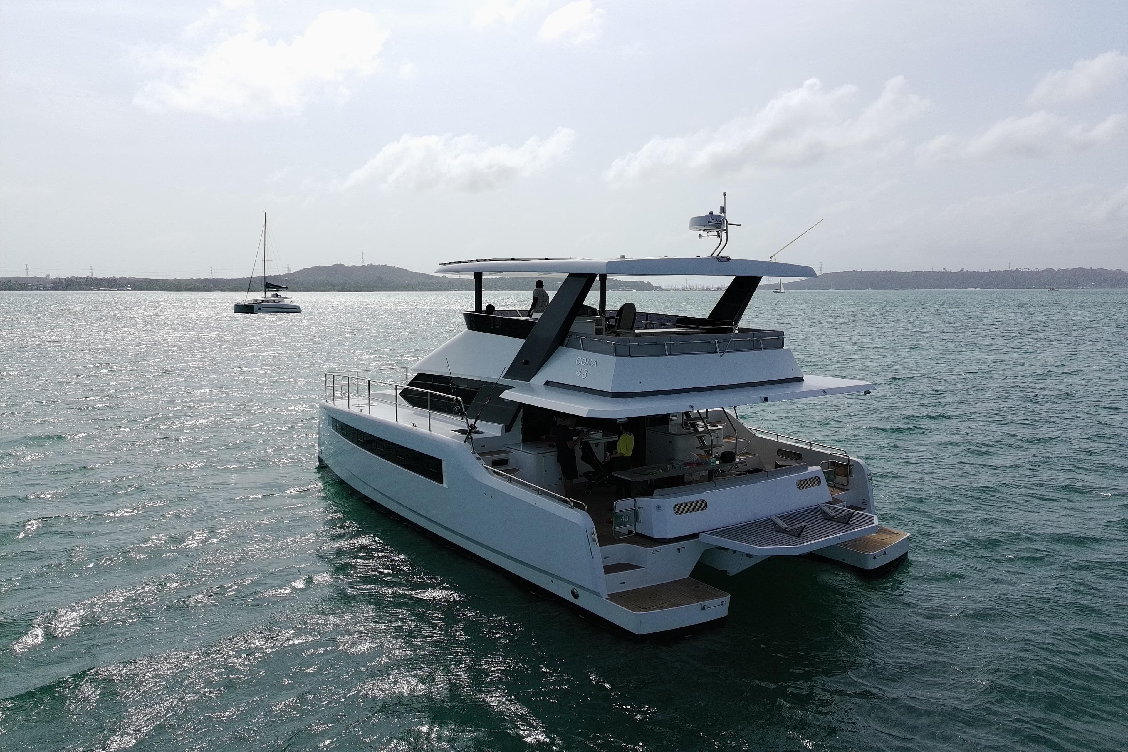 2024 Cora 48 yacht cruising on serene waters under a cloudy sky.