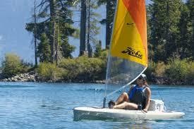 Person sailing a 2024 Hobie Outback kayak on a serene lake.