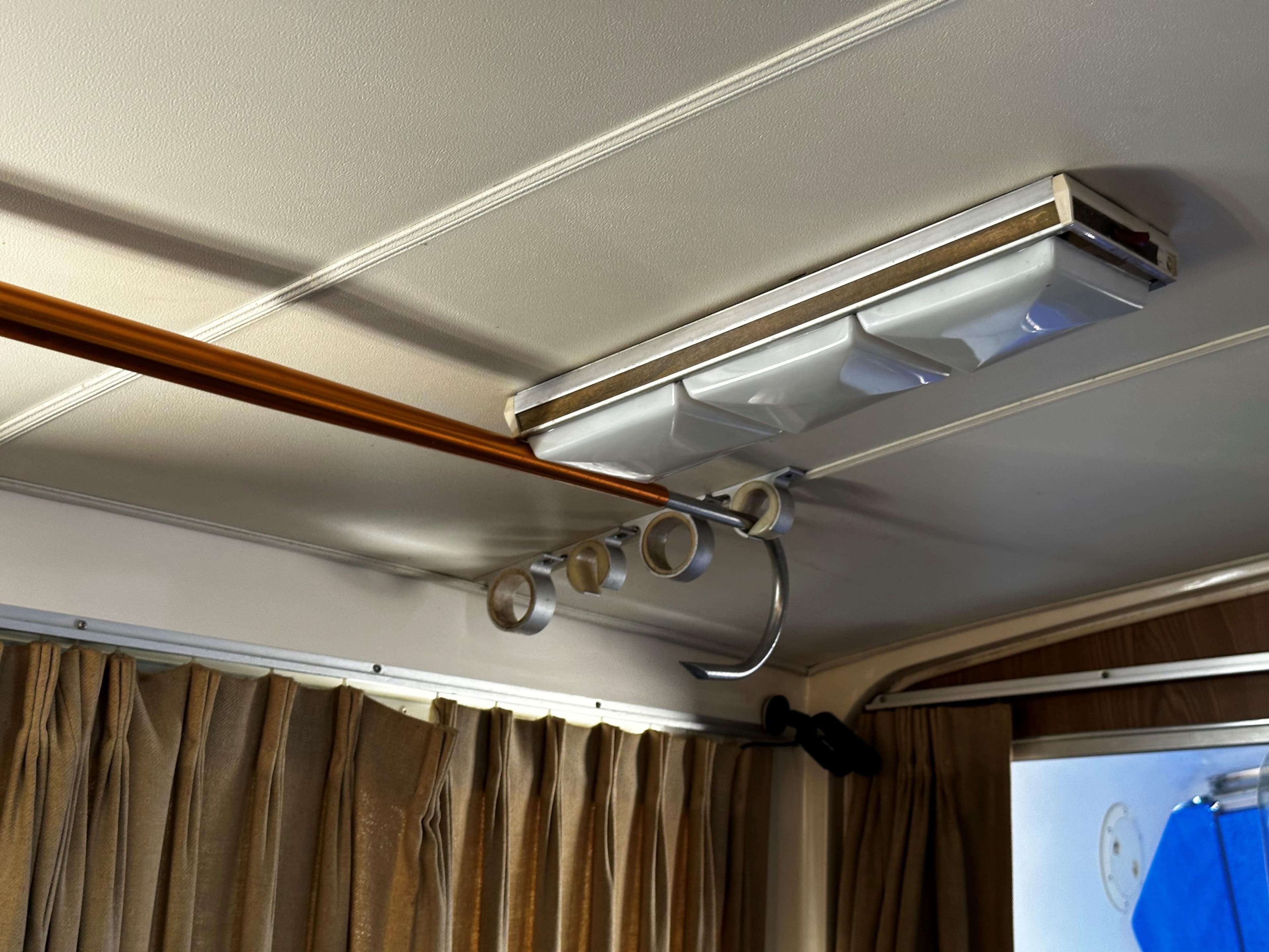 Ceiling interior of a 1980 Bertram 33 Sport Fisherman boat with rod holders and light fixture.