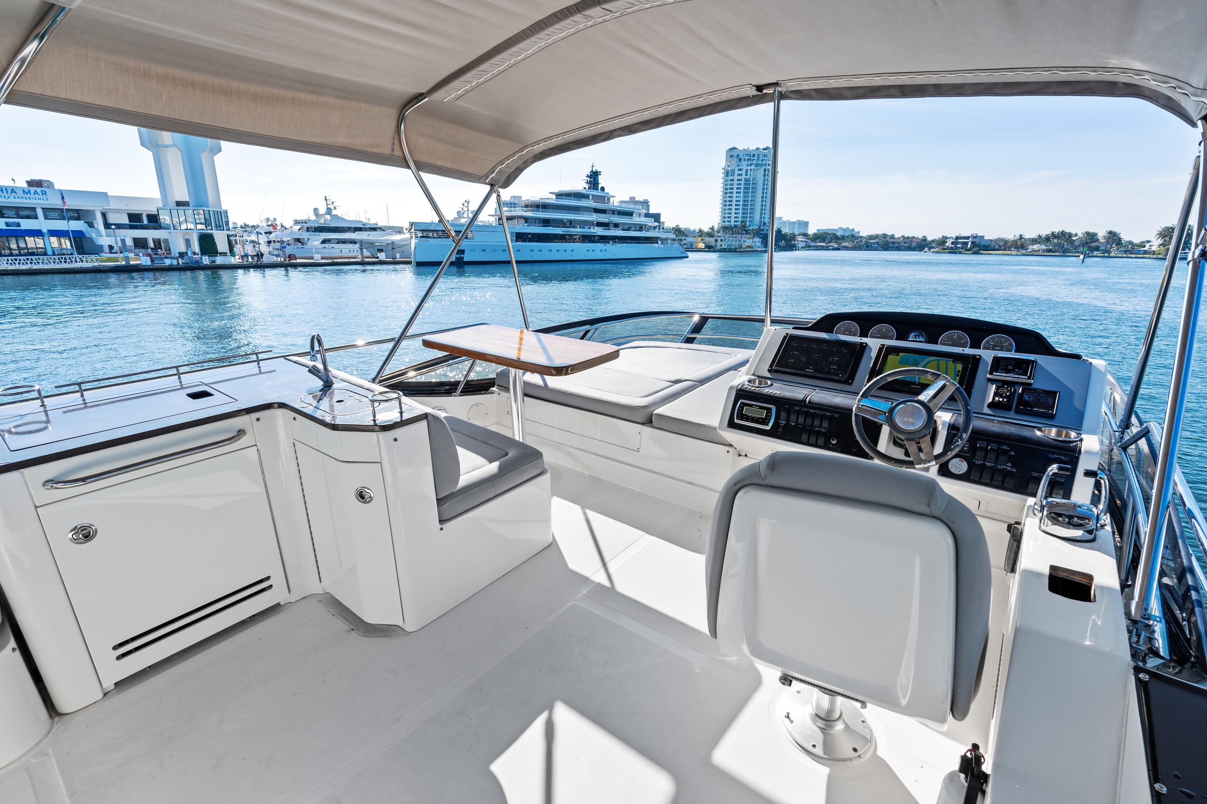 Flybridge of 2014 Sea Ray 510 Fly yacht with helm and seating, overlooking marina.